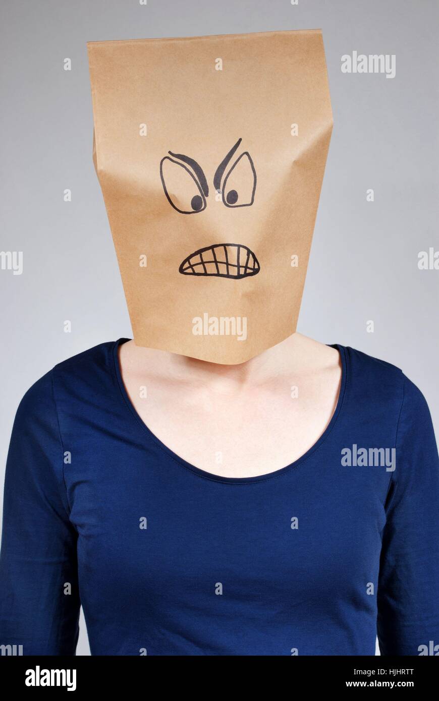 a mad looking person with paper bag head on a gray background Stock