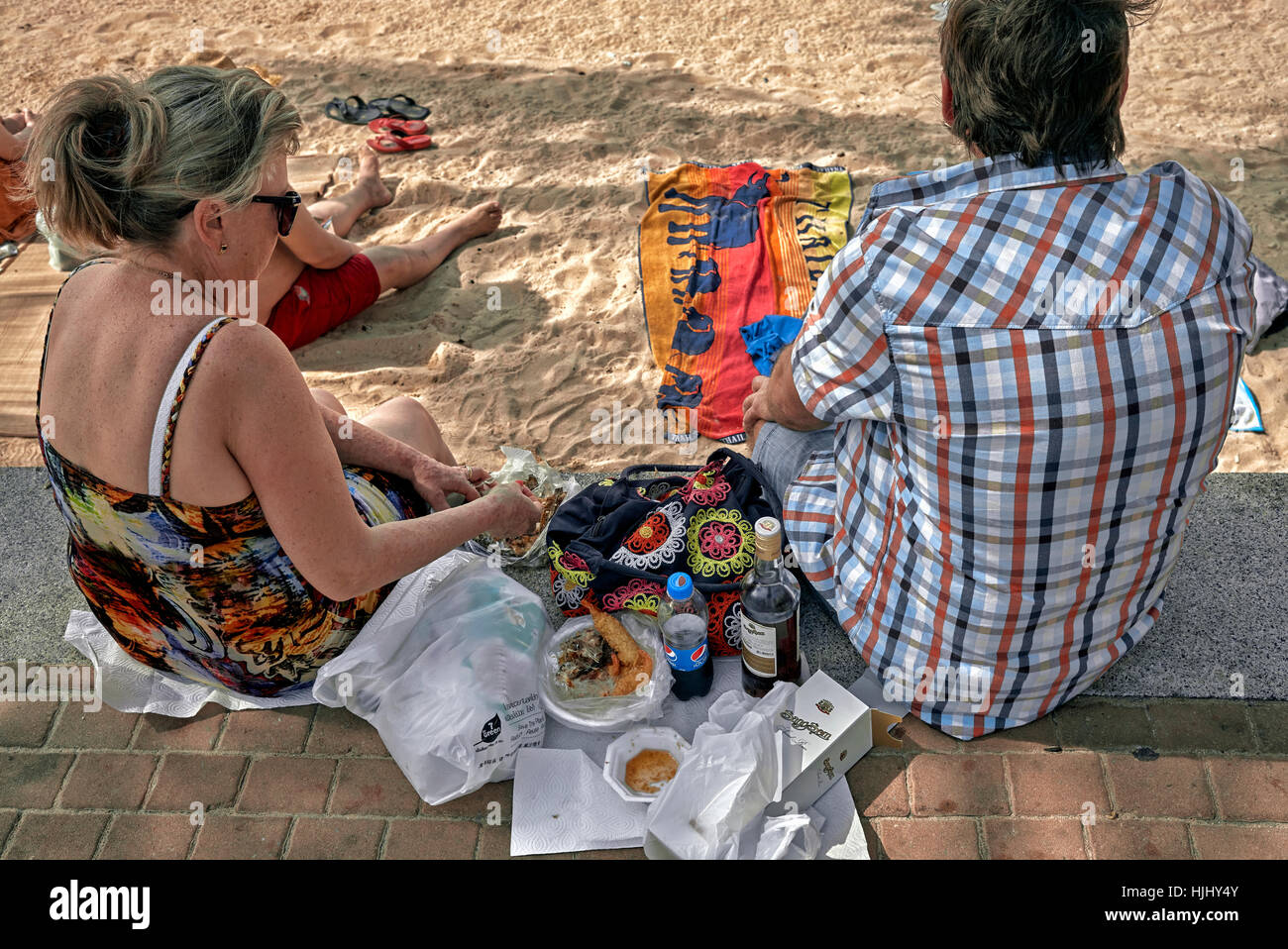 Couple enjoying day out at the beach with food and alcohol drinks. Stock Photo