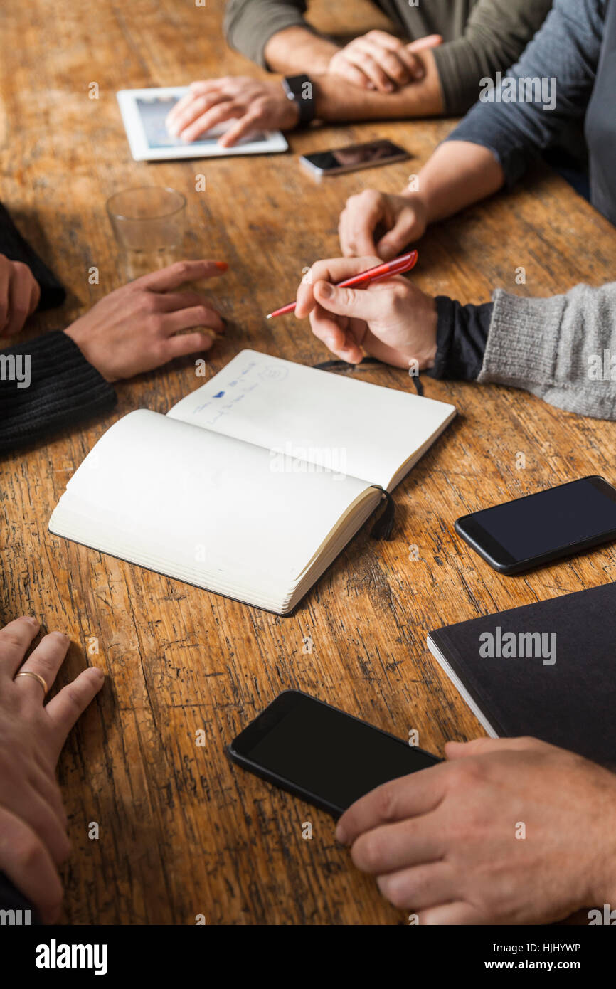 Coworkers working on a project on wooden table Stock Photo - Alamy