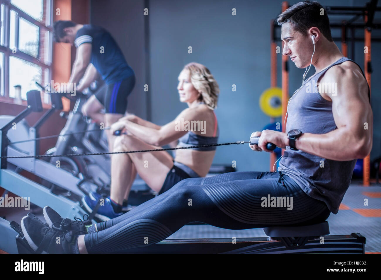Young man exercising at rowing machine in gym Stock Photo - Alamy