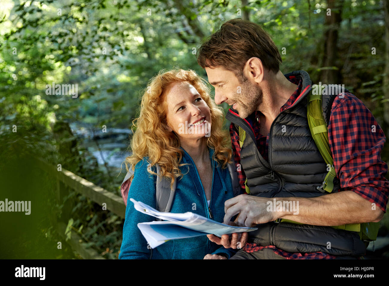Hiking couple holding map Stock Photo - Alamy