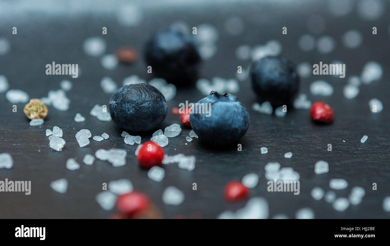 Blueberry berries with sugar granules close-up on a dark background with red berries Stock Photo