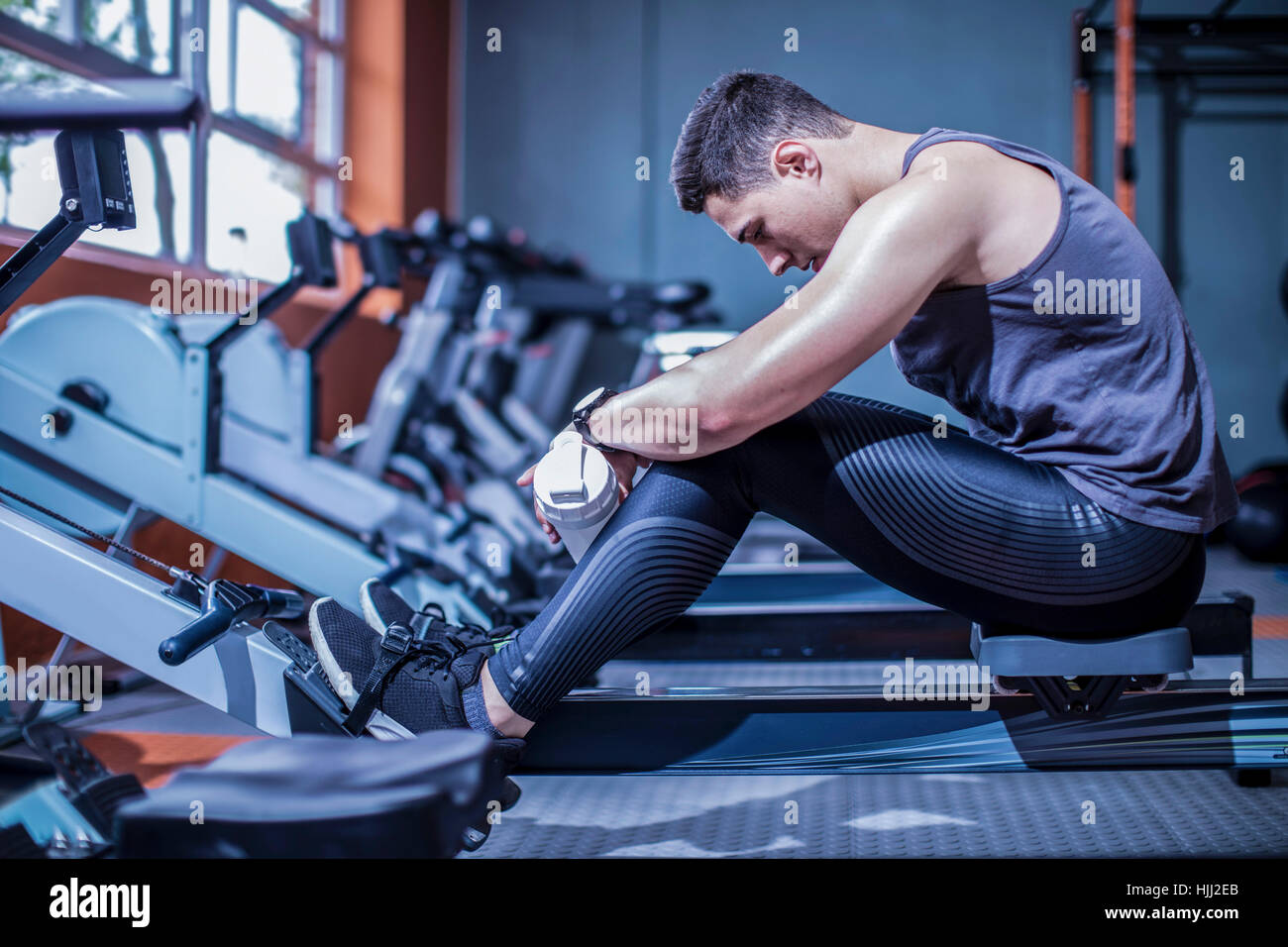 Young man having a break at rowing machine in gym Stock Photo - Alamy