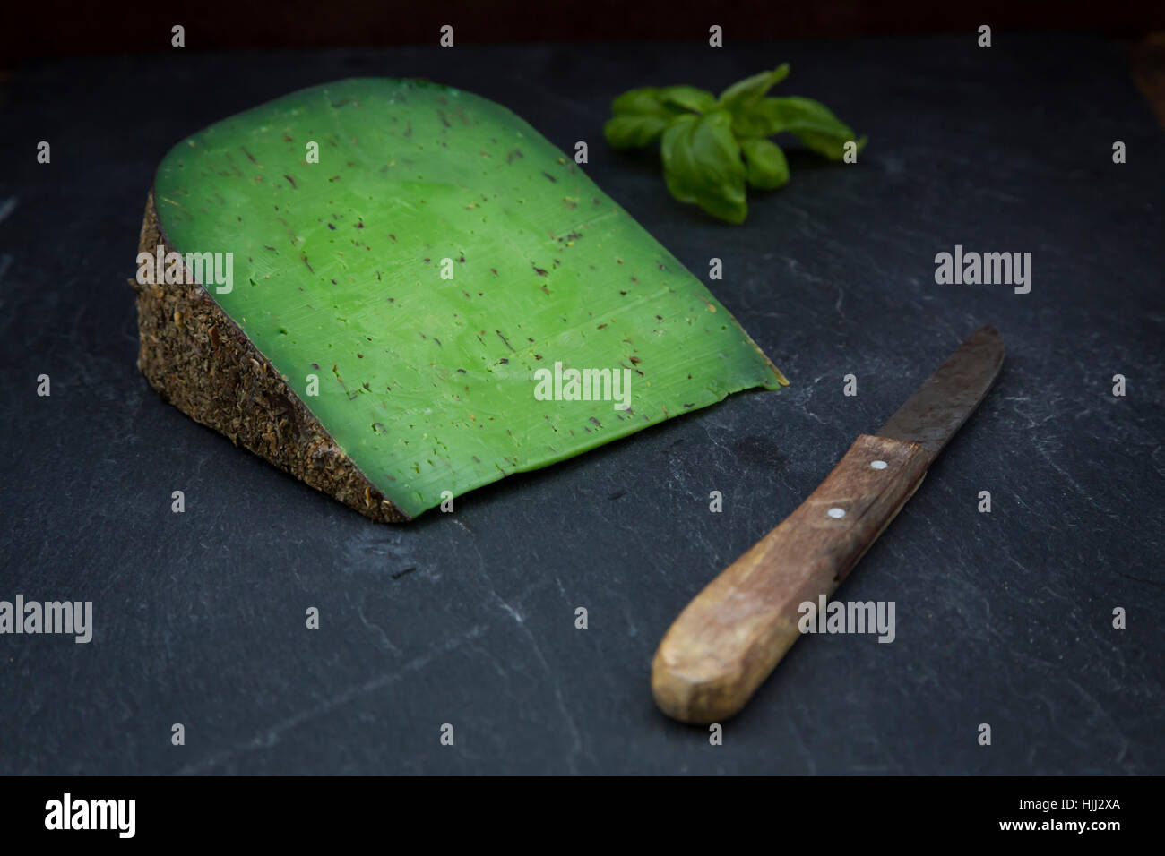 Piece of basil cheese, kitchen knife and basil leaves on slate Stock ...