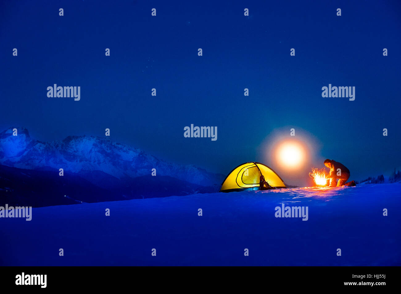 Senior man camping in snow-covered landscape at full moon Stock Photo