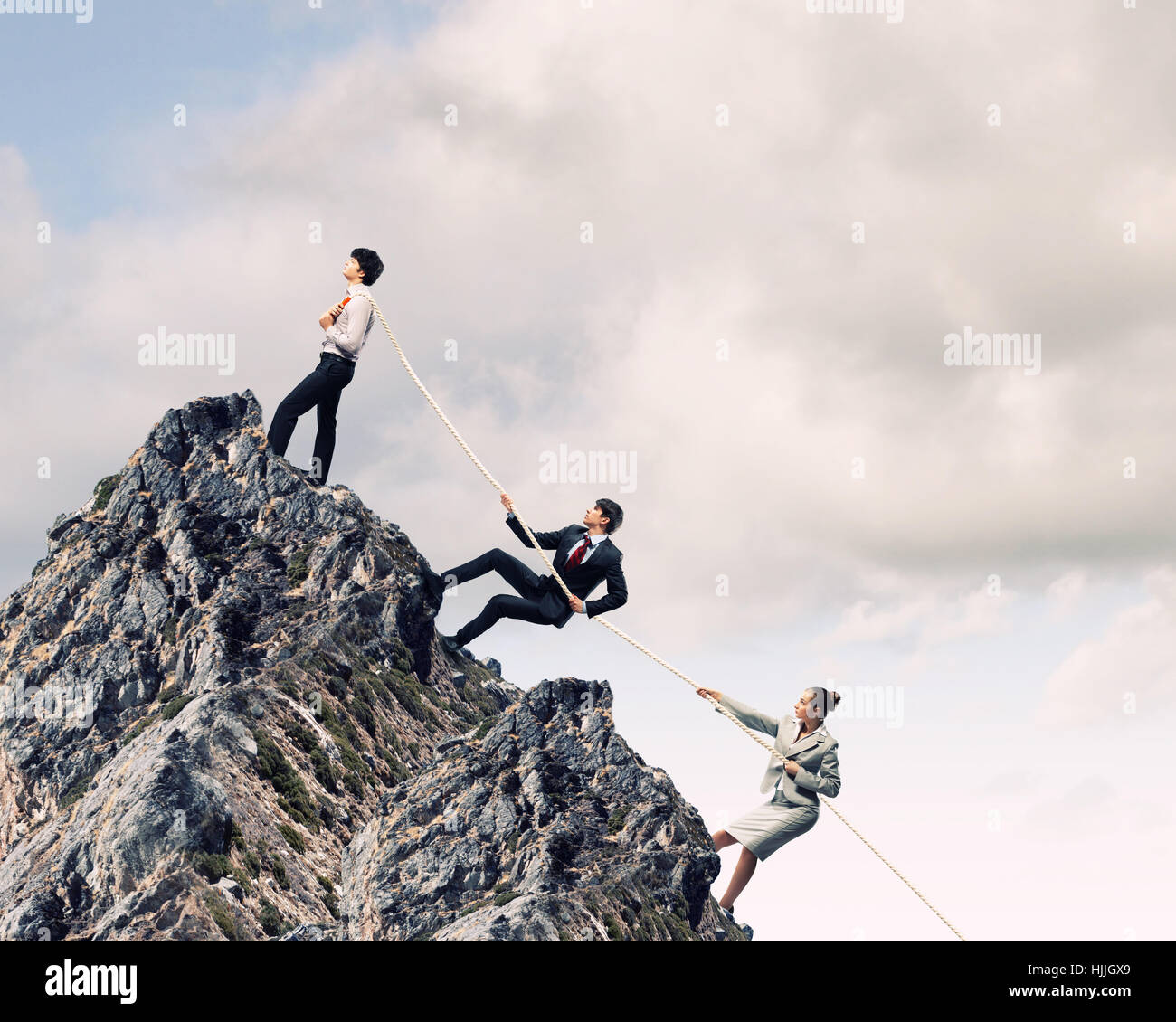 Image of three businesspeople pulling rope atop of mountain Stock Photo ...