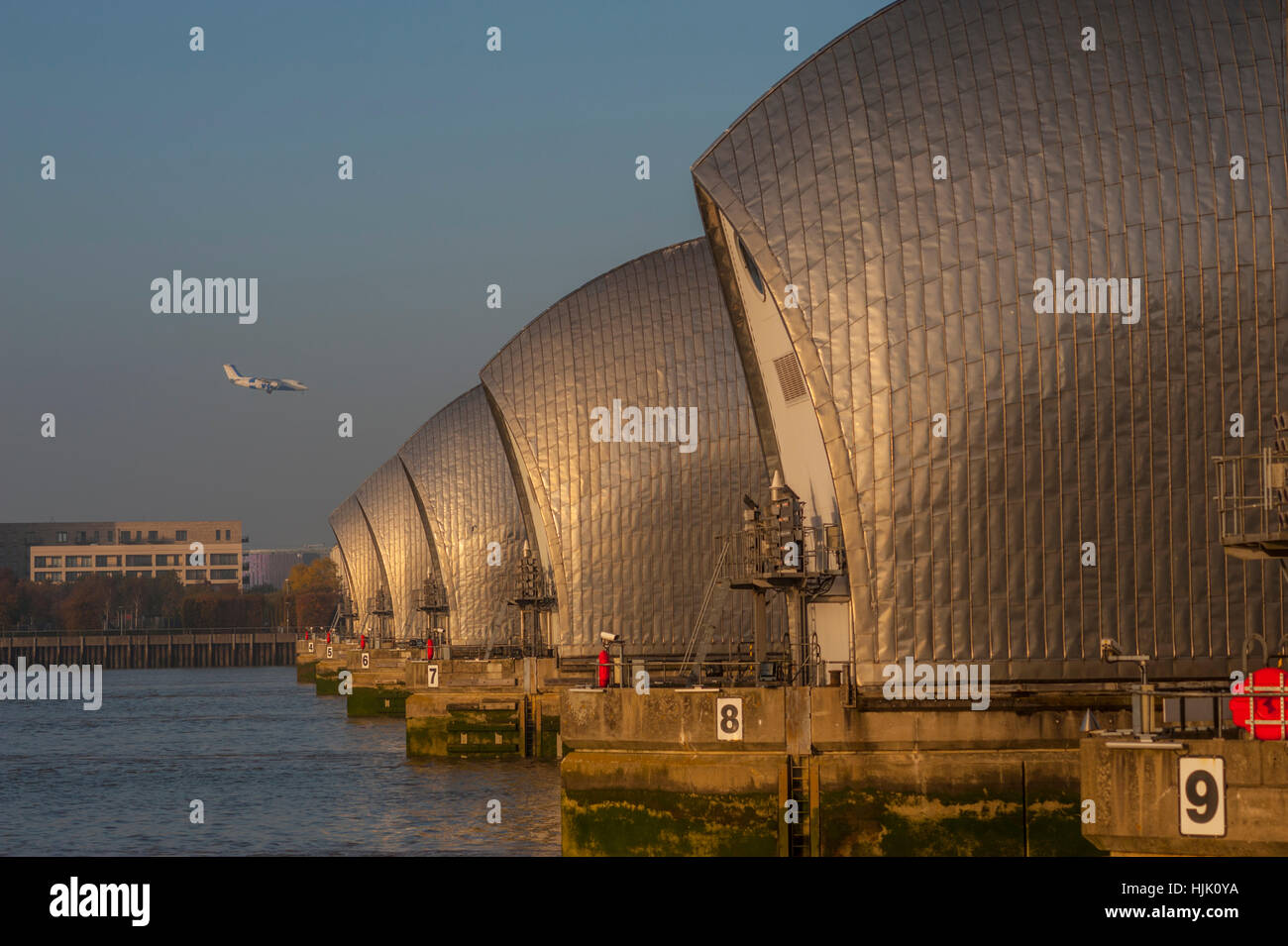 The thames Barrier at Woolwich Kent. in evening light. with a plane coming into the london city airport Stock Photo