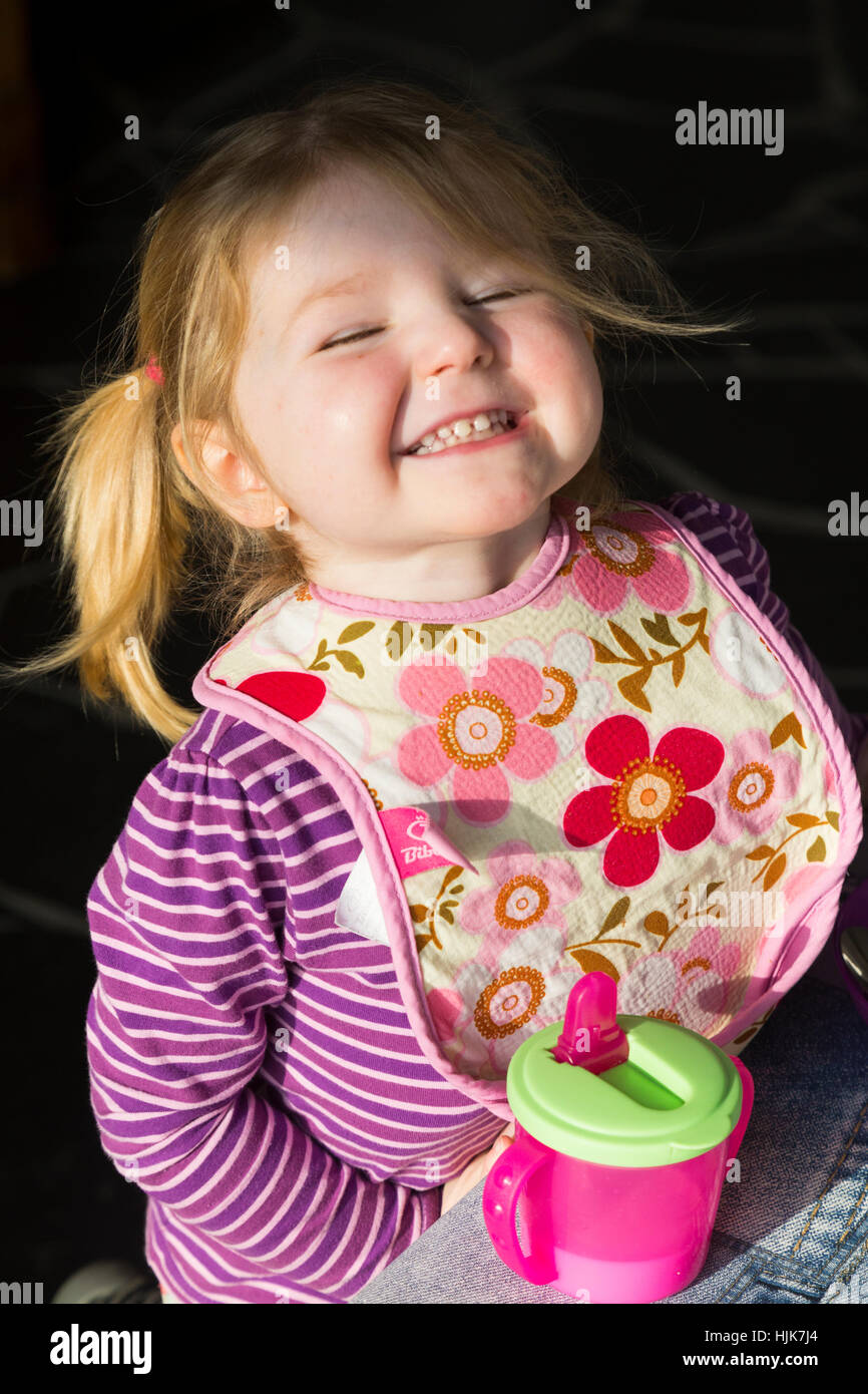 Toddler girl happy and content to wear a bib to protect her clothes at ...
