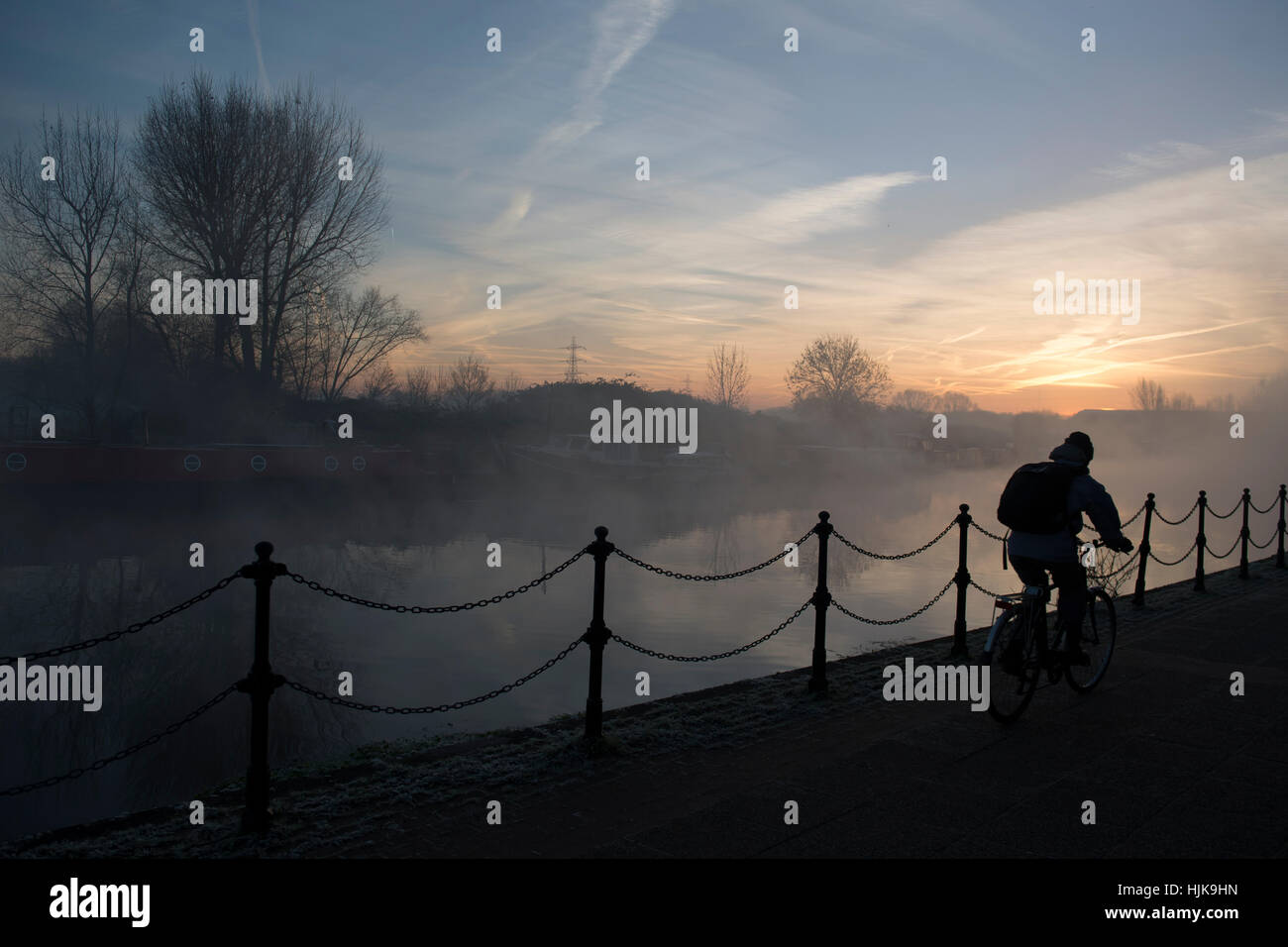 A person cycles along the River Lea, at dawn, in Hackney, London Stock Photo