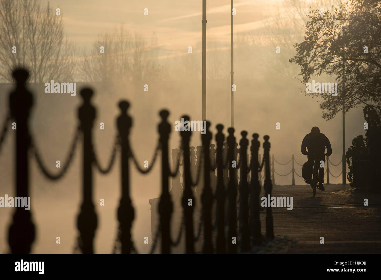 A person cycles along the tow path at dawn, by the River Lea in London Stock Photo