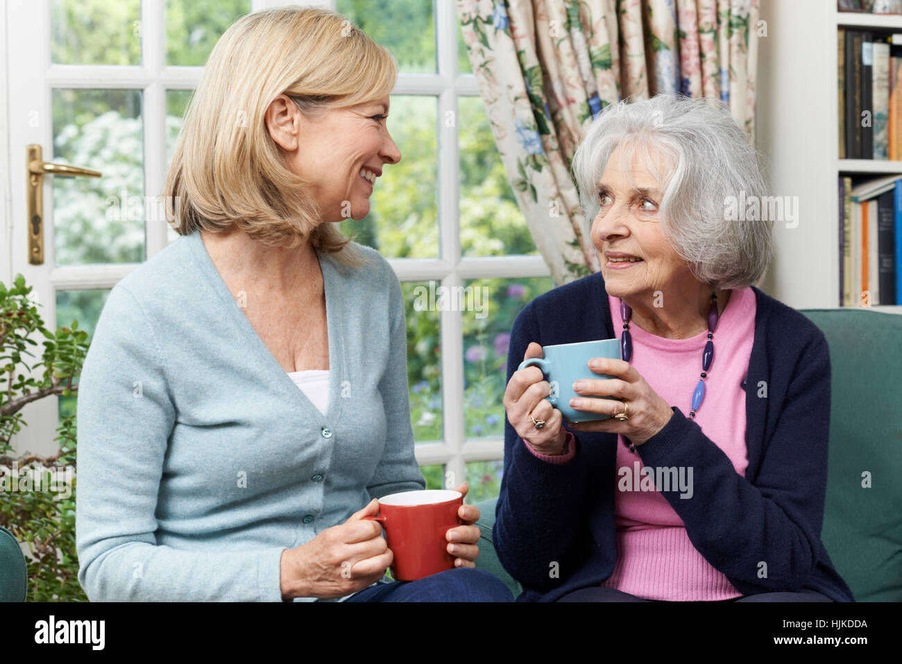 Woman Taking Time To Visit Senior Female Neighbor And Talk Stock Photo