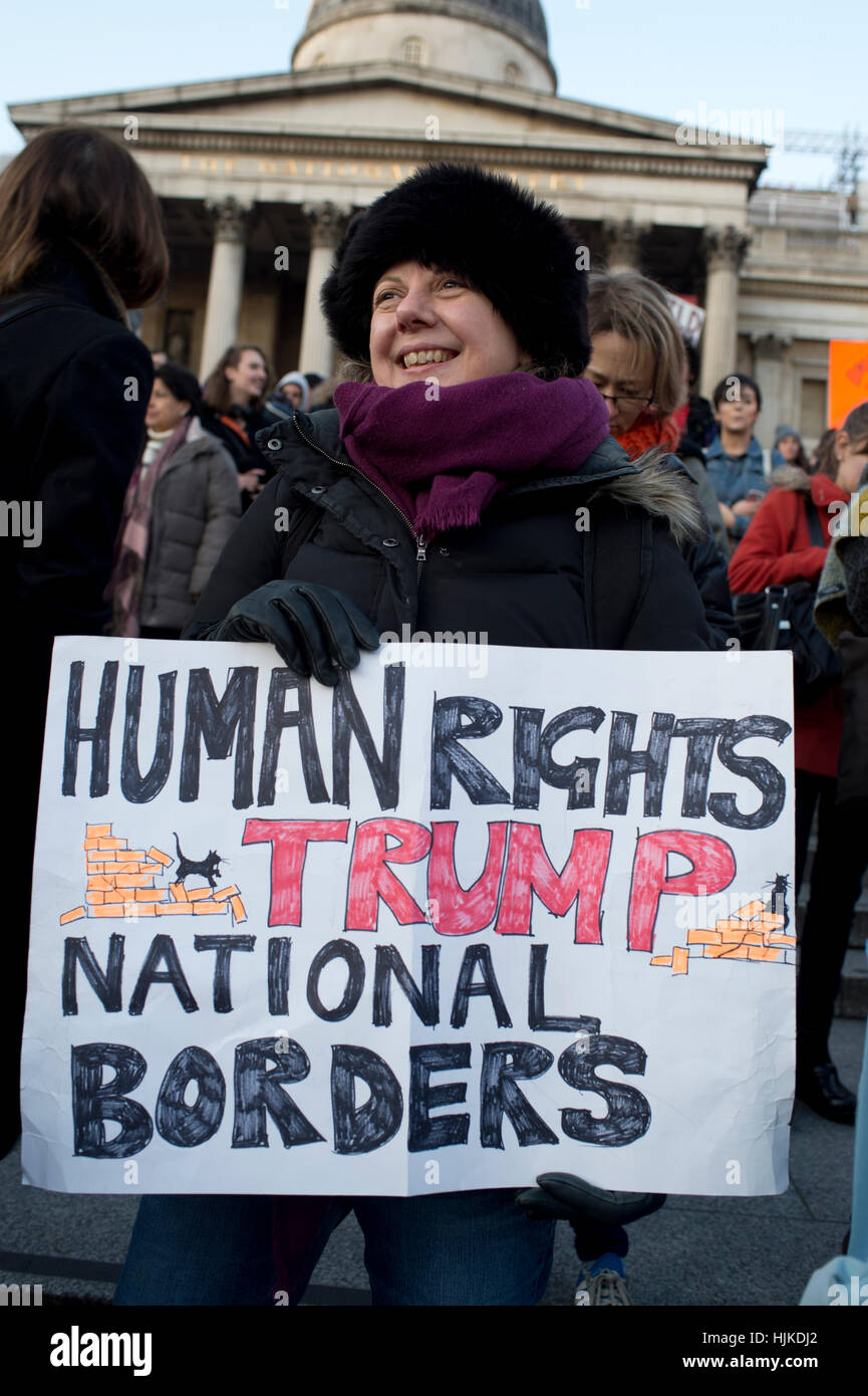 Women's Anti-Trump march. A woman in Trafalgar Square holds a placard saying ' Human Rights trump National borders'. Stock Photo
