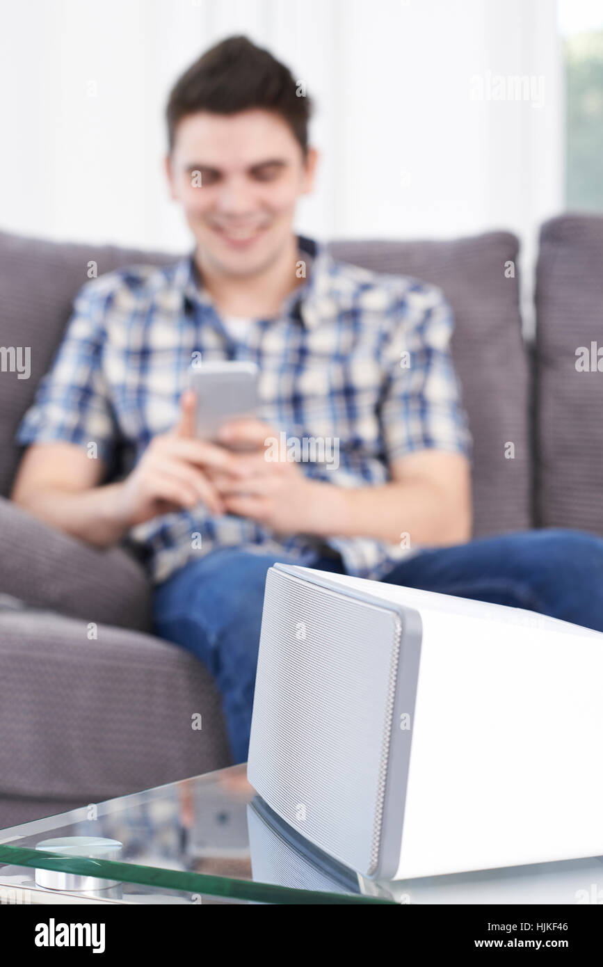 Man Streams Music From Mobile Phone To Wireless Speaker Stock Photo