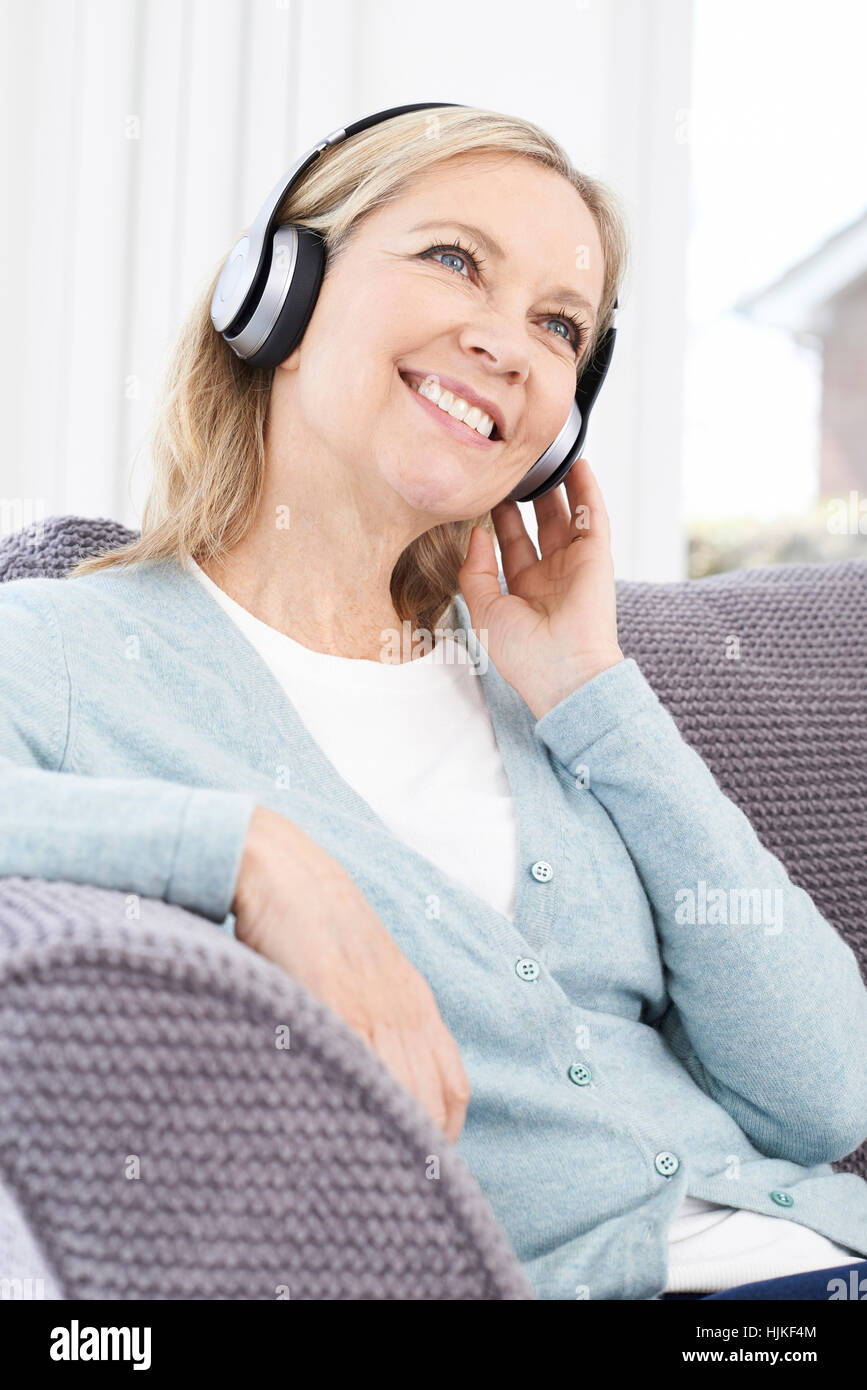 Mature Woman Listening To Music On Wireless Headphones Stock Photo - Alamy