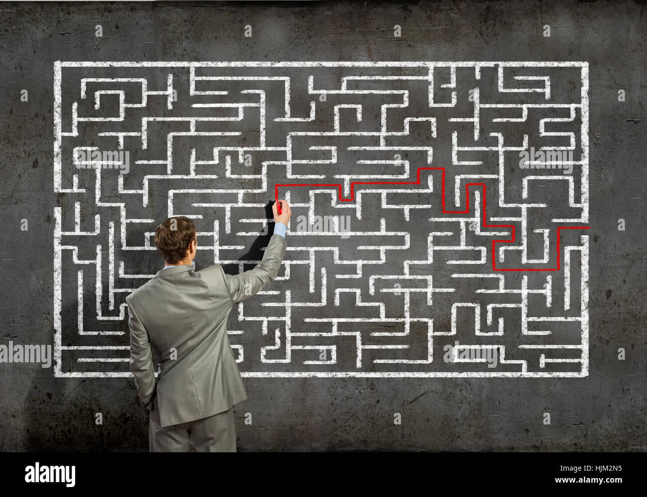 Trying To Find Back view image of young businessman trying to find way out of maze ...