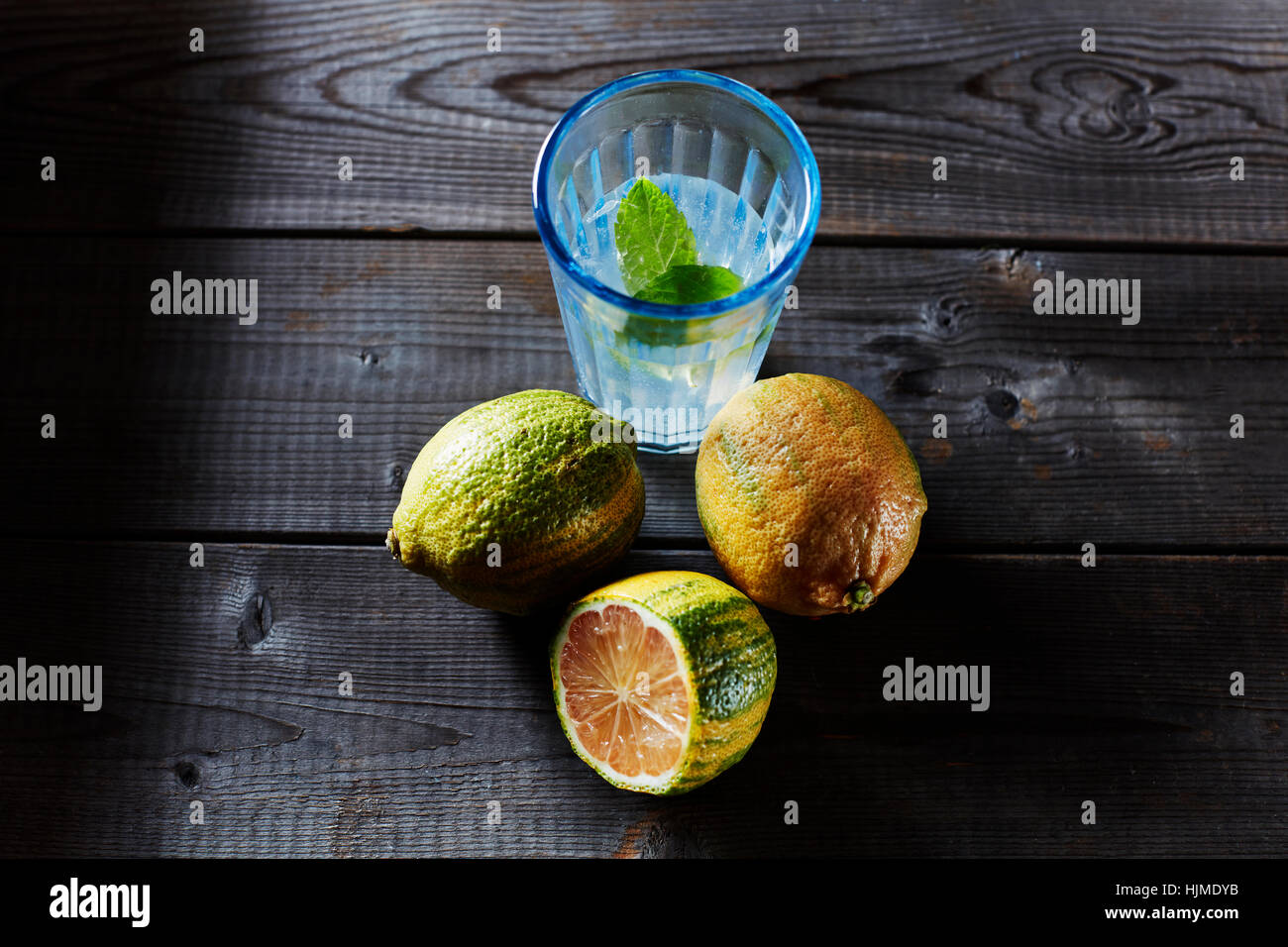 Whole and sliced tiger lemons and glass of infused water Stock Photo