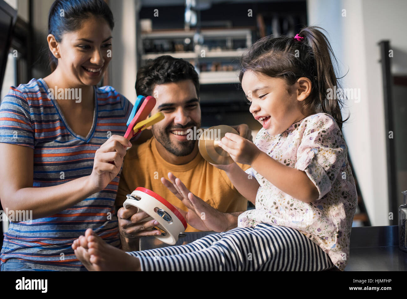 Mother and father making music with their little daughter Stock Photo