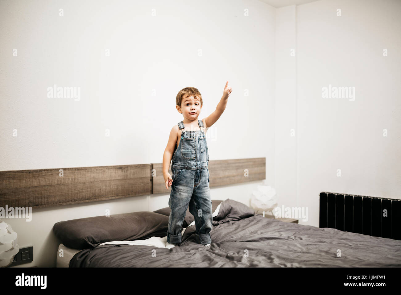 Little boy standing on the bed of his parents pointing on something