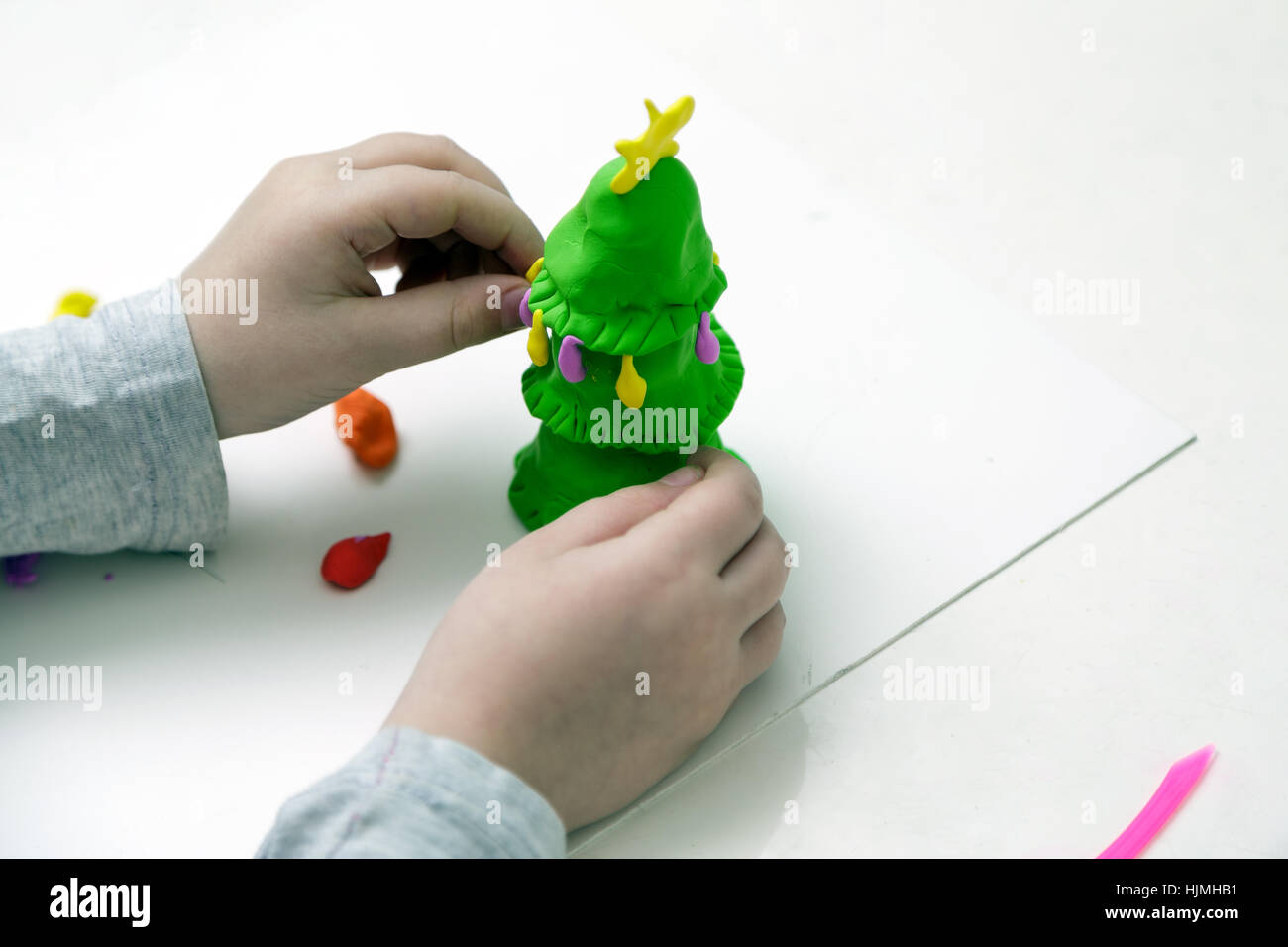 Children's hands mould a New Year tree from plasticine Stock Photo