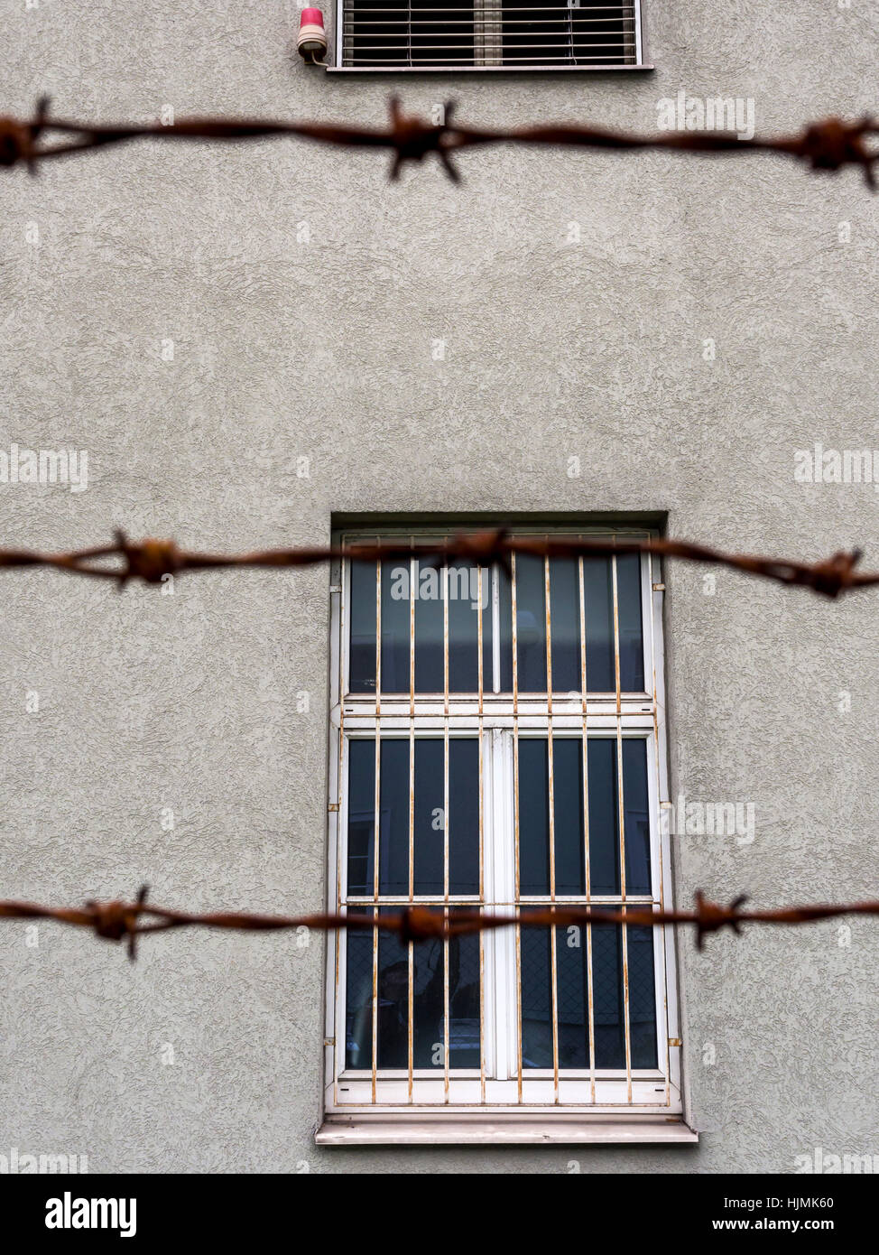 Barred window behind barbed wire Stock Photo