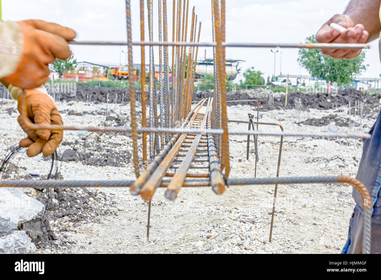 Worker is using white chalk to mark place for tying rebar of newly constructed footing frame