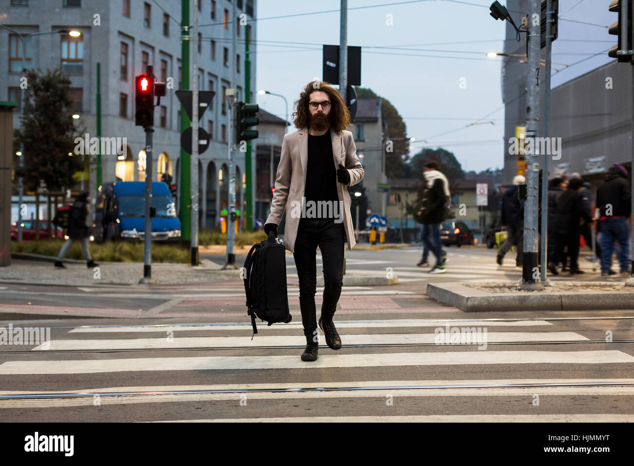 Stylish young man with bag crossing street on zebra crossing Stock Photo