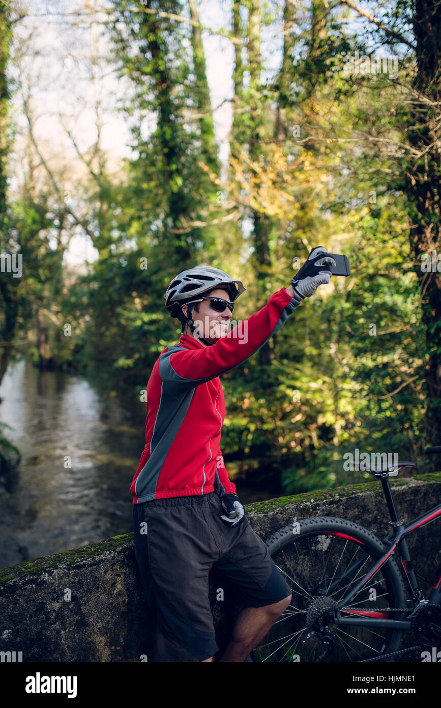 Mountain biker taking picture in forest with his smart phone Stock Photo