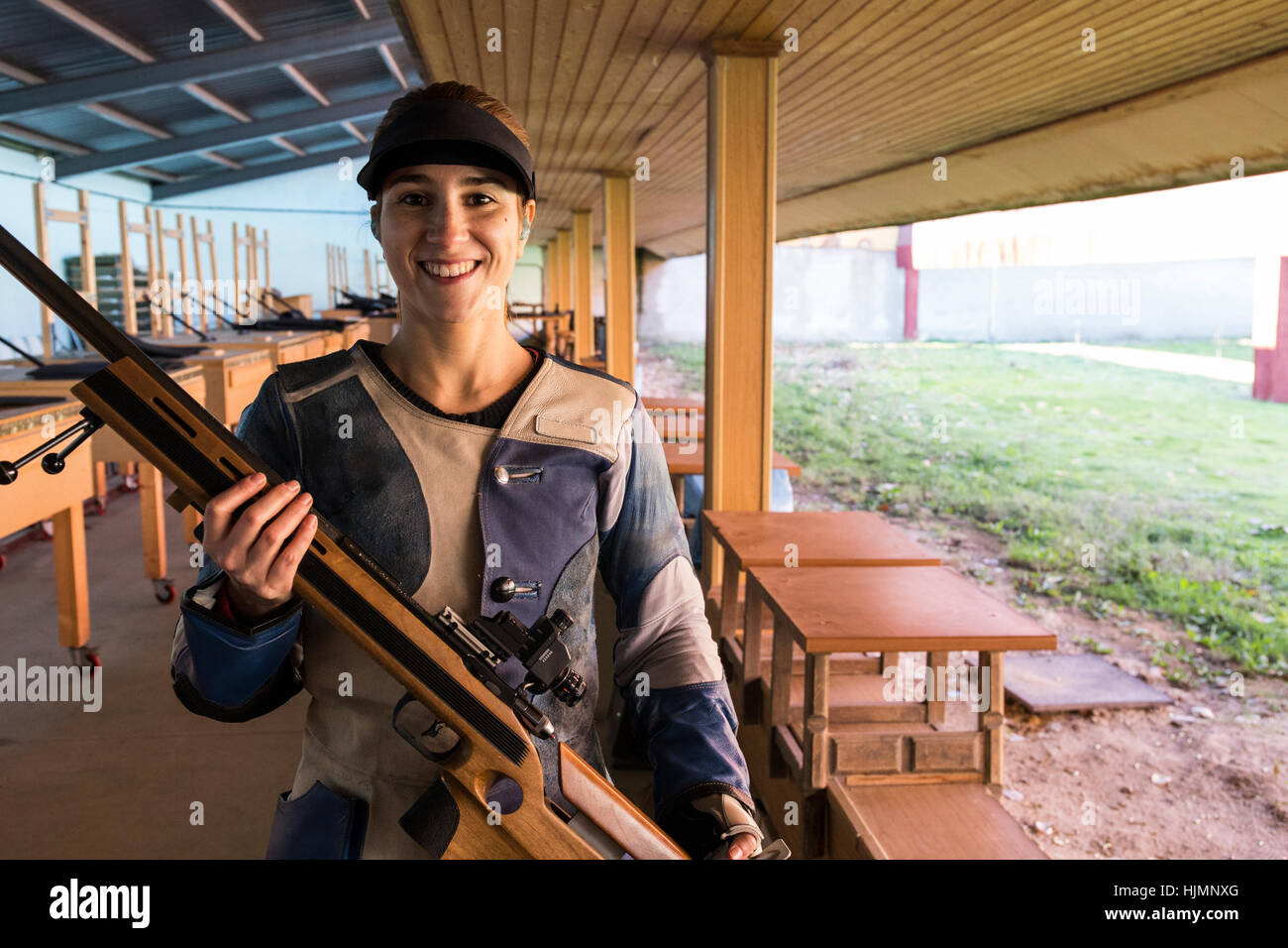 Portrait of a smiling woman holding her sporting rifle in a shooting ...