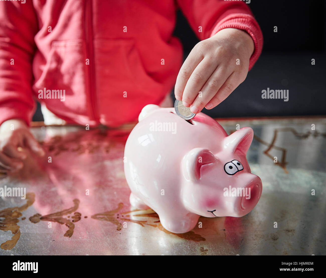 Girl putting coin into piggy bank Stock Photo - Alamy