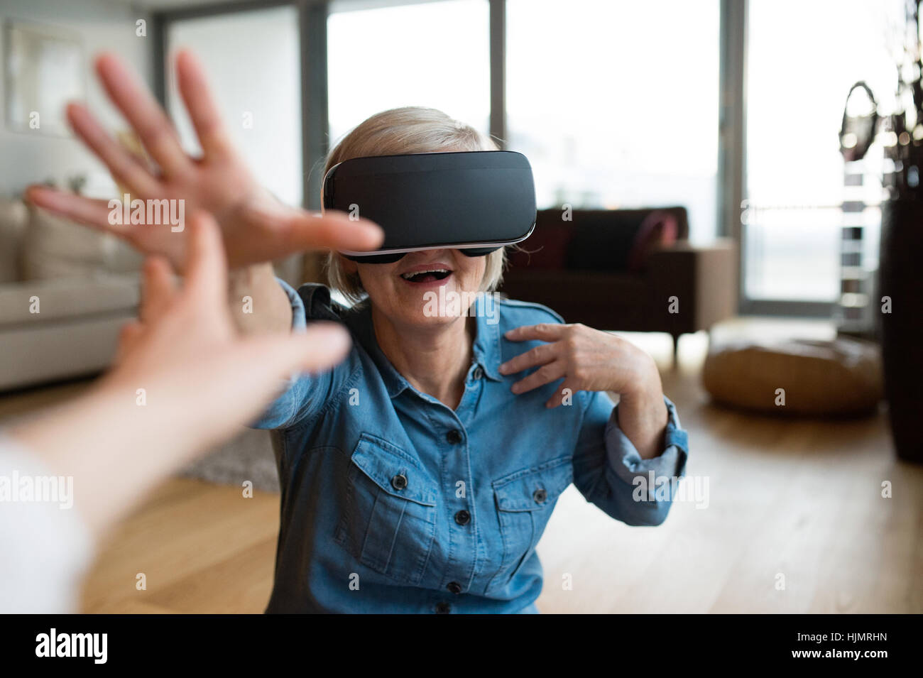 Senior Woman Wearing Virtual Reality Goggles At Home Stock Photo