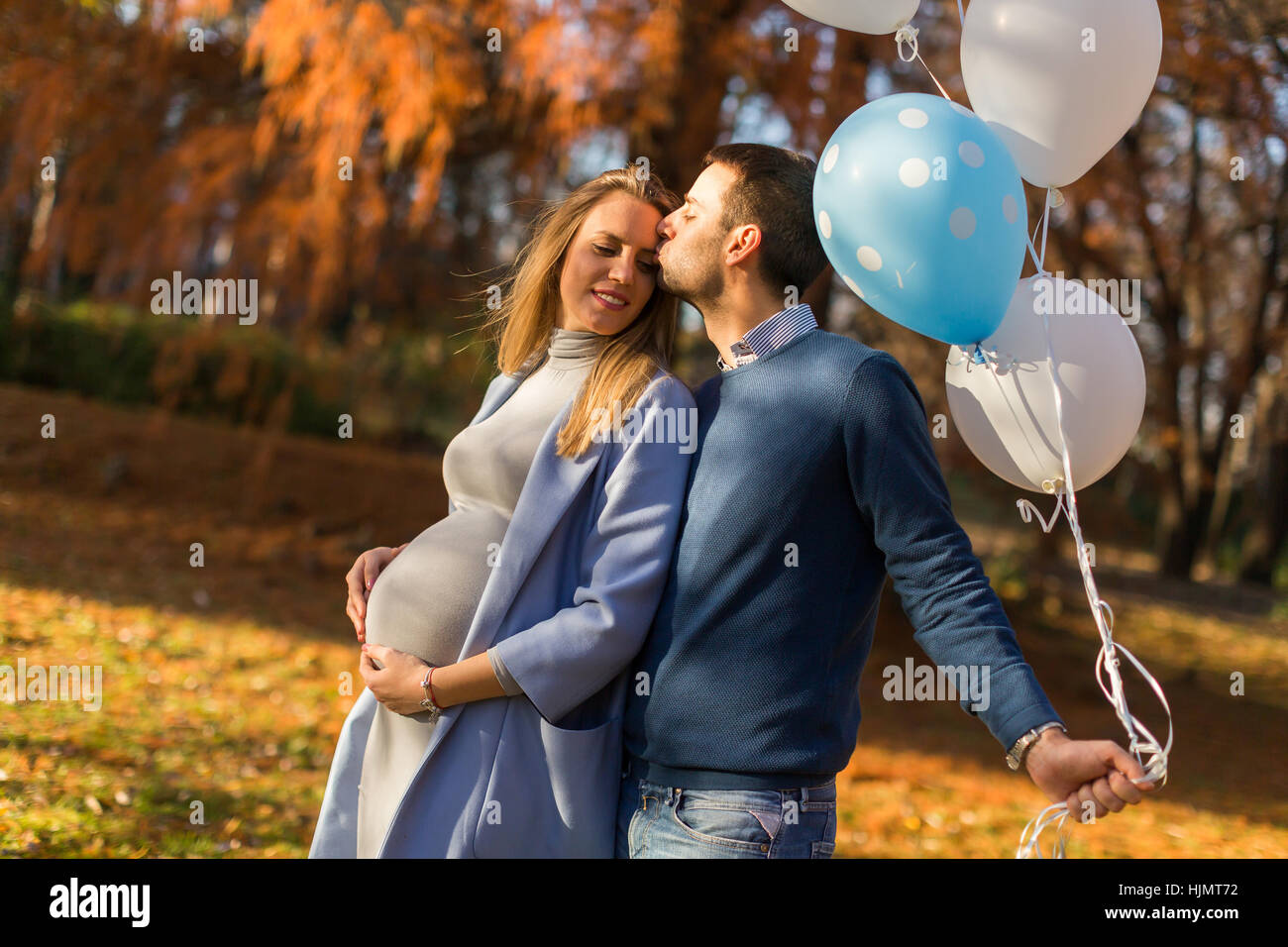 Young pregnant woman and man posing in autumn park with balloons in ...