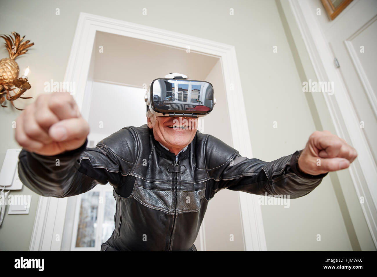 Senior man in motorcycle suit wearing VR glasses Stock Photo