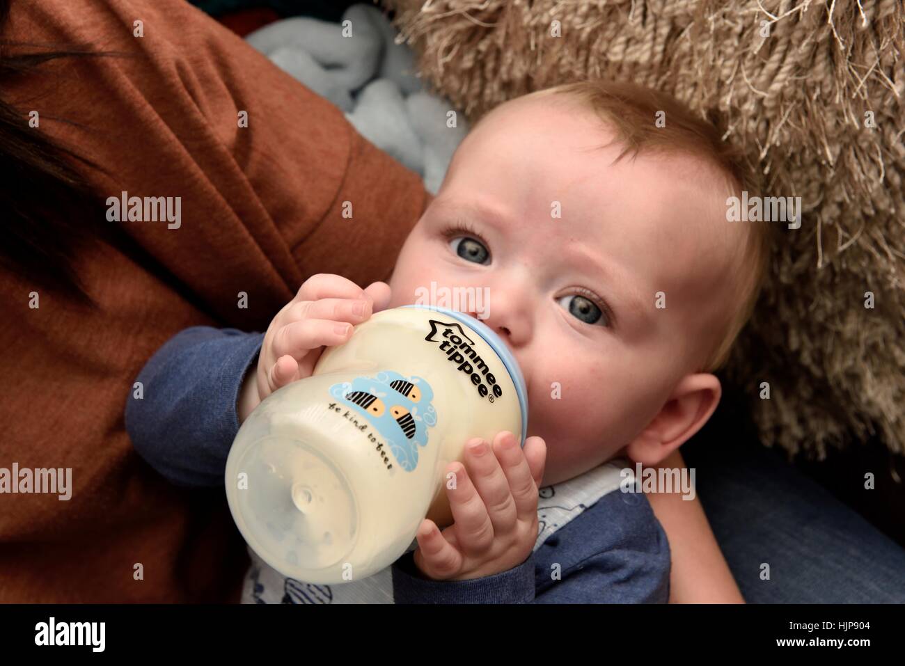 A baby boy holding his bottle whilst feeding. Stock Photo