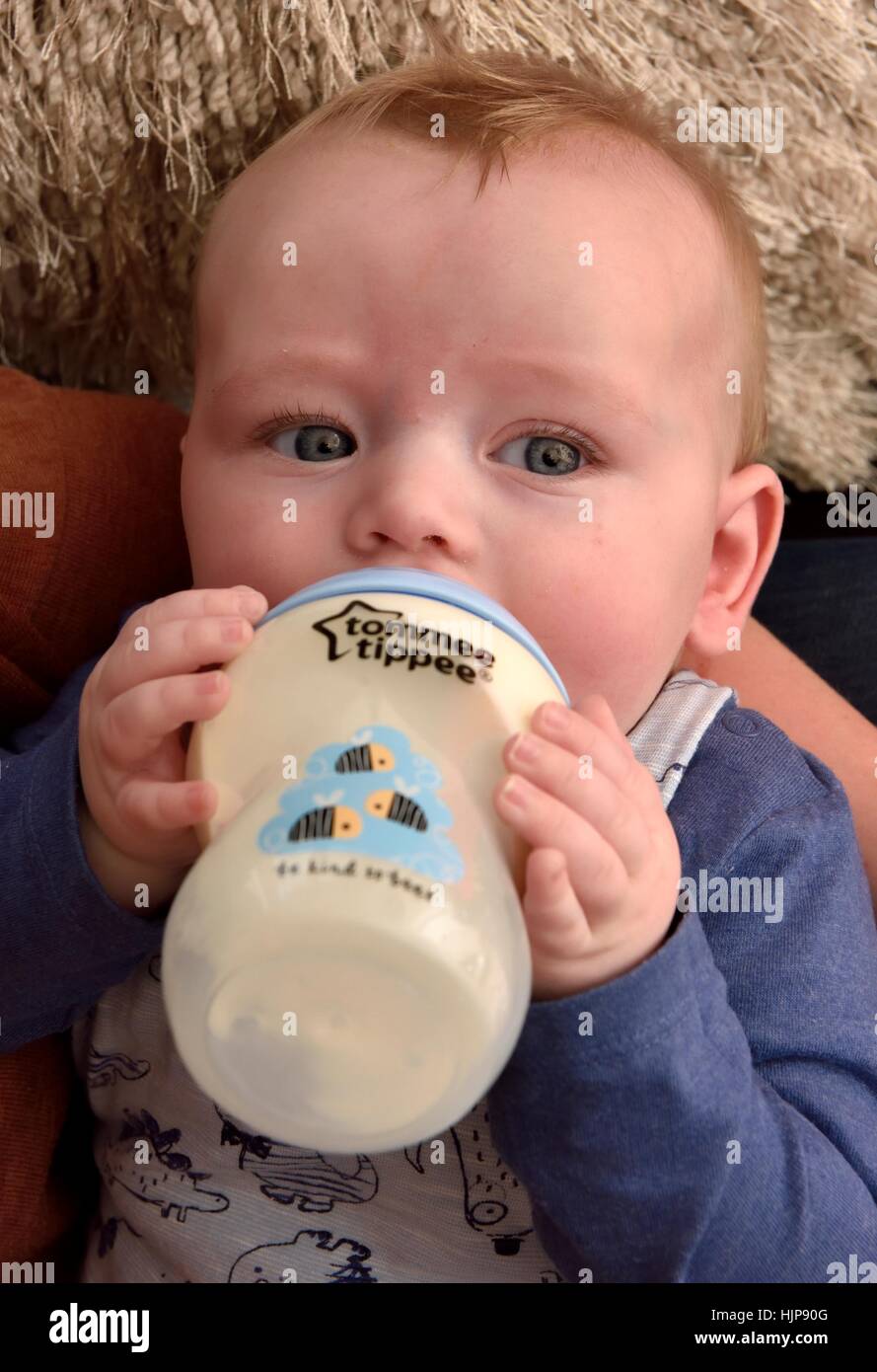 A baby boy holding his bottle whilst feeding. Stock Photo
