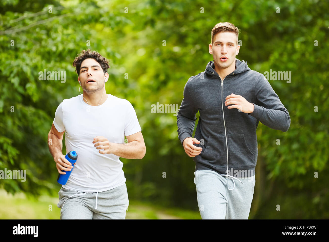 Two young men jogging at the park and training together Stock Photo