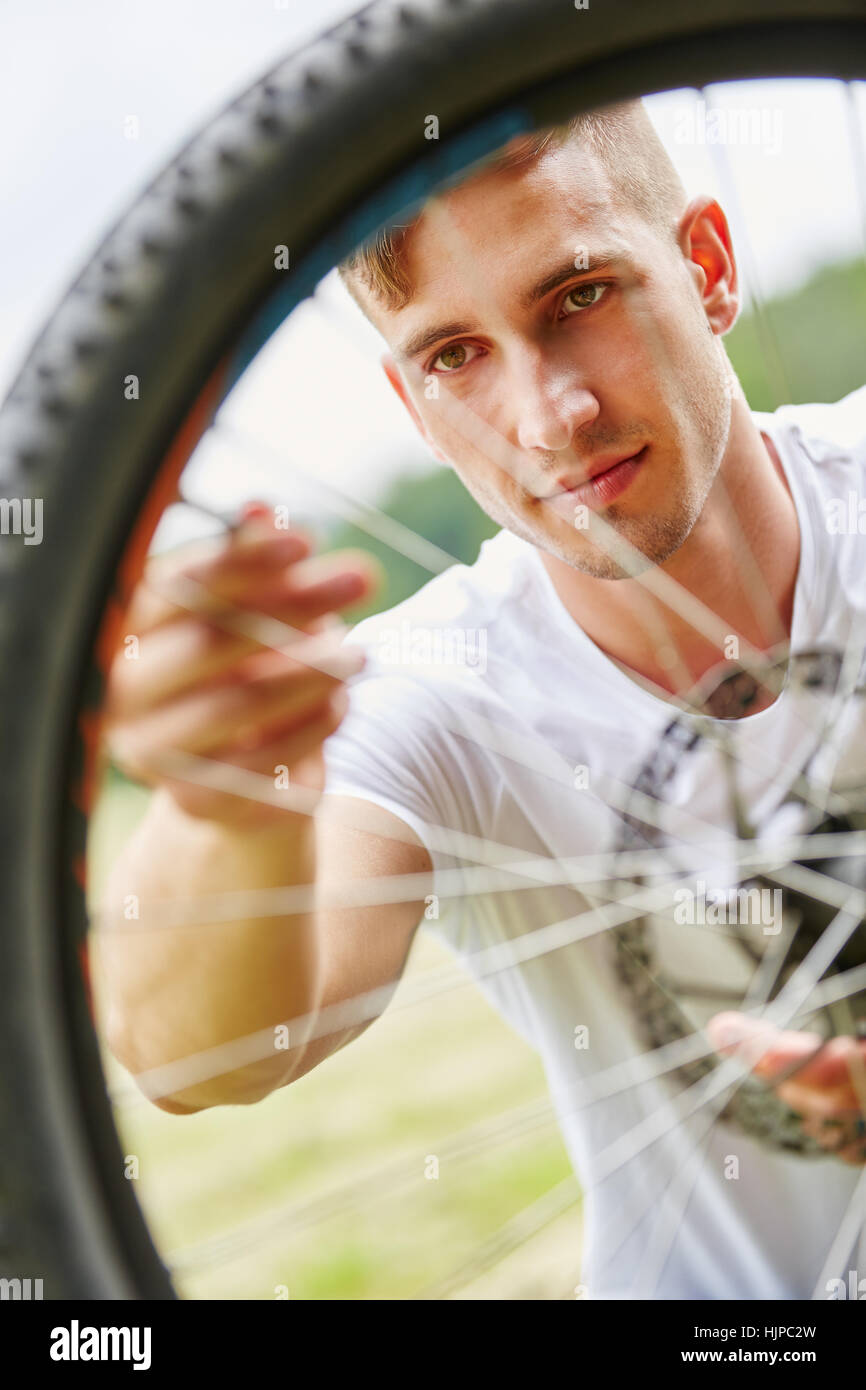 Man fixing wheel of bike in summer in nature Stock Photo