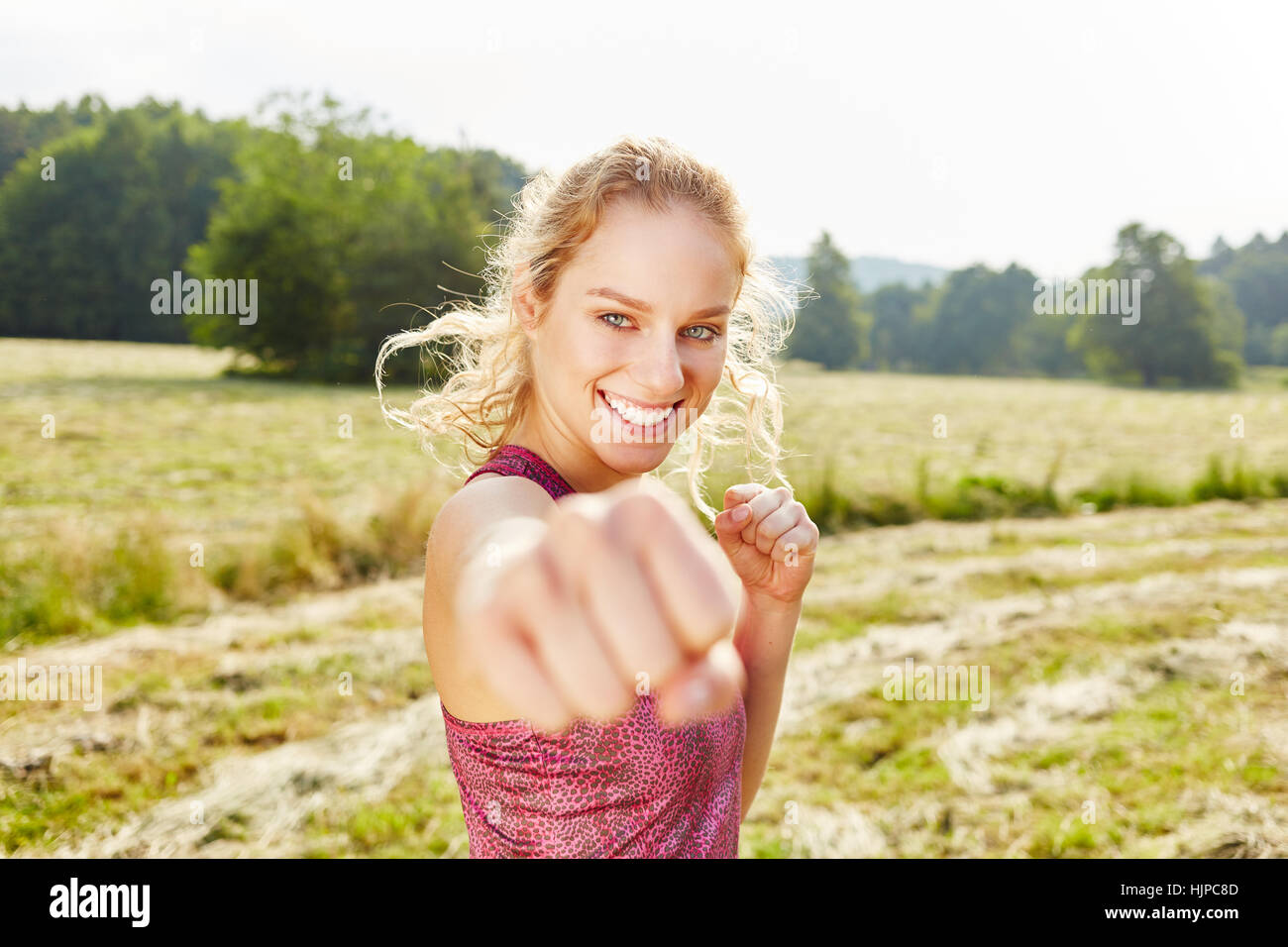 Young woman clenching a fist while practicing boxing in the nature Stock Photo