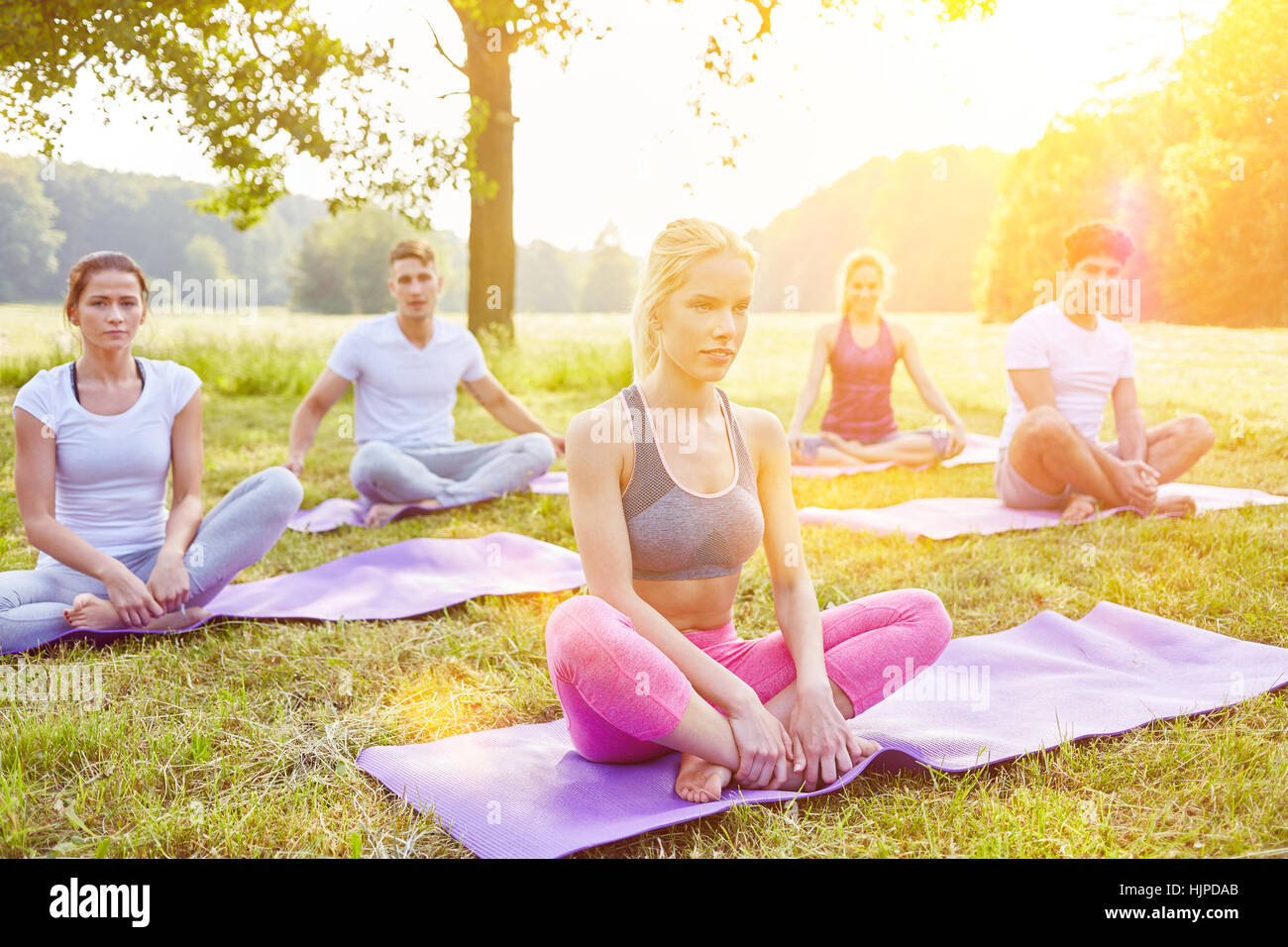 Yoga group doing relaxation exercise in summer at park Stock Photo