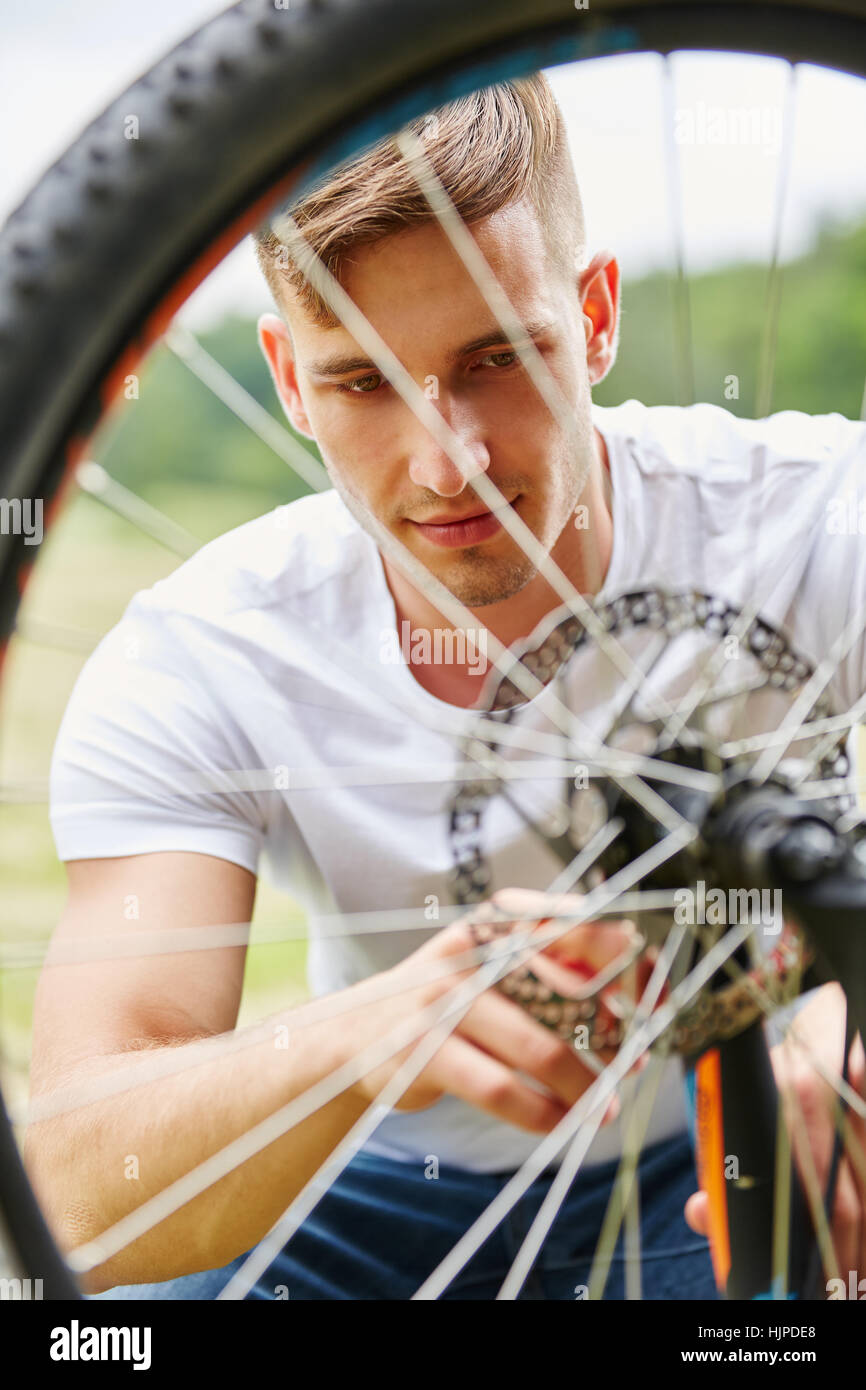 Teenager giving maintenance to bicycle in summer Stock Photo