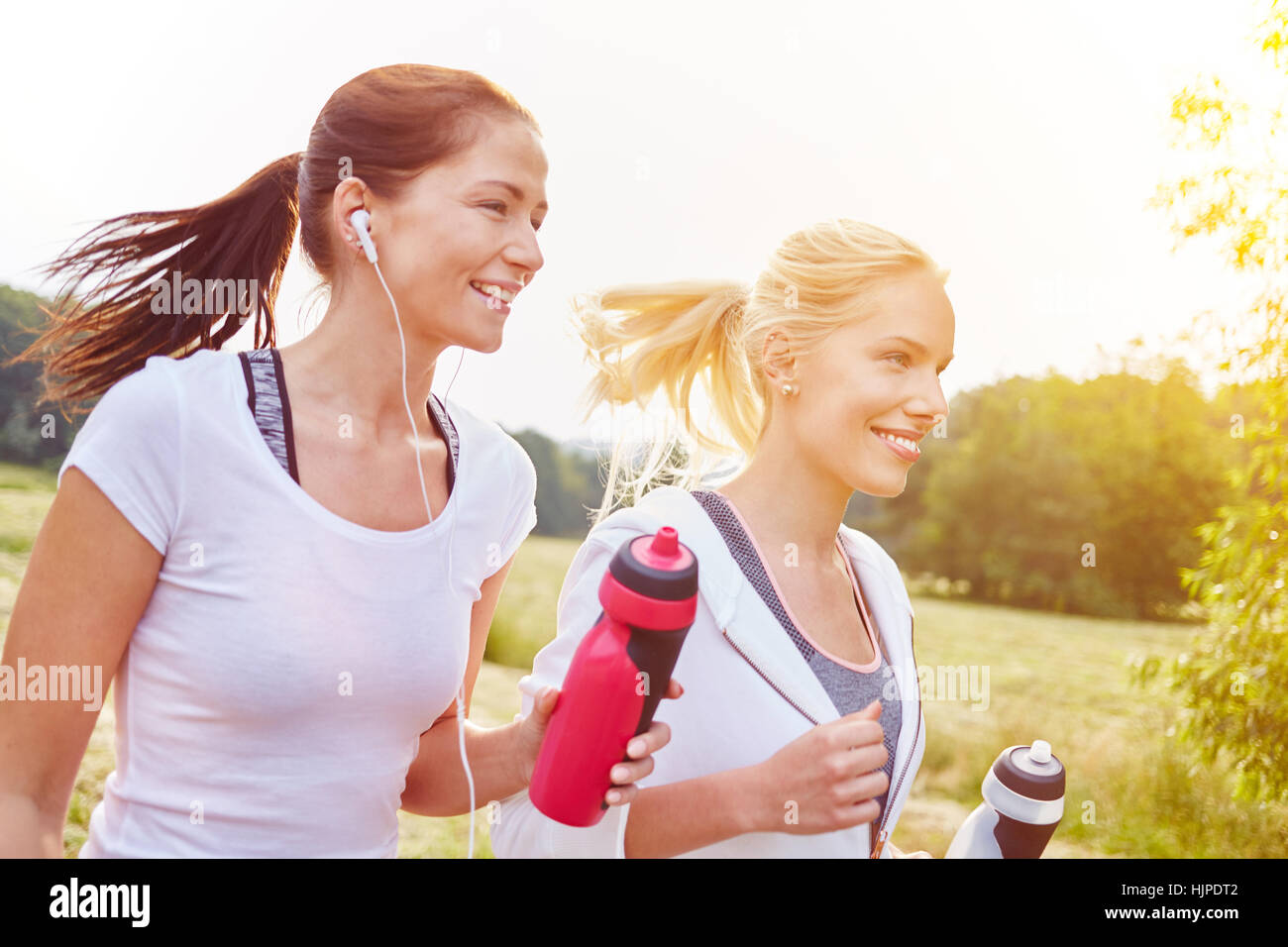 Two young women running together in the park Stock Photo