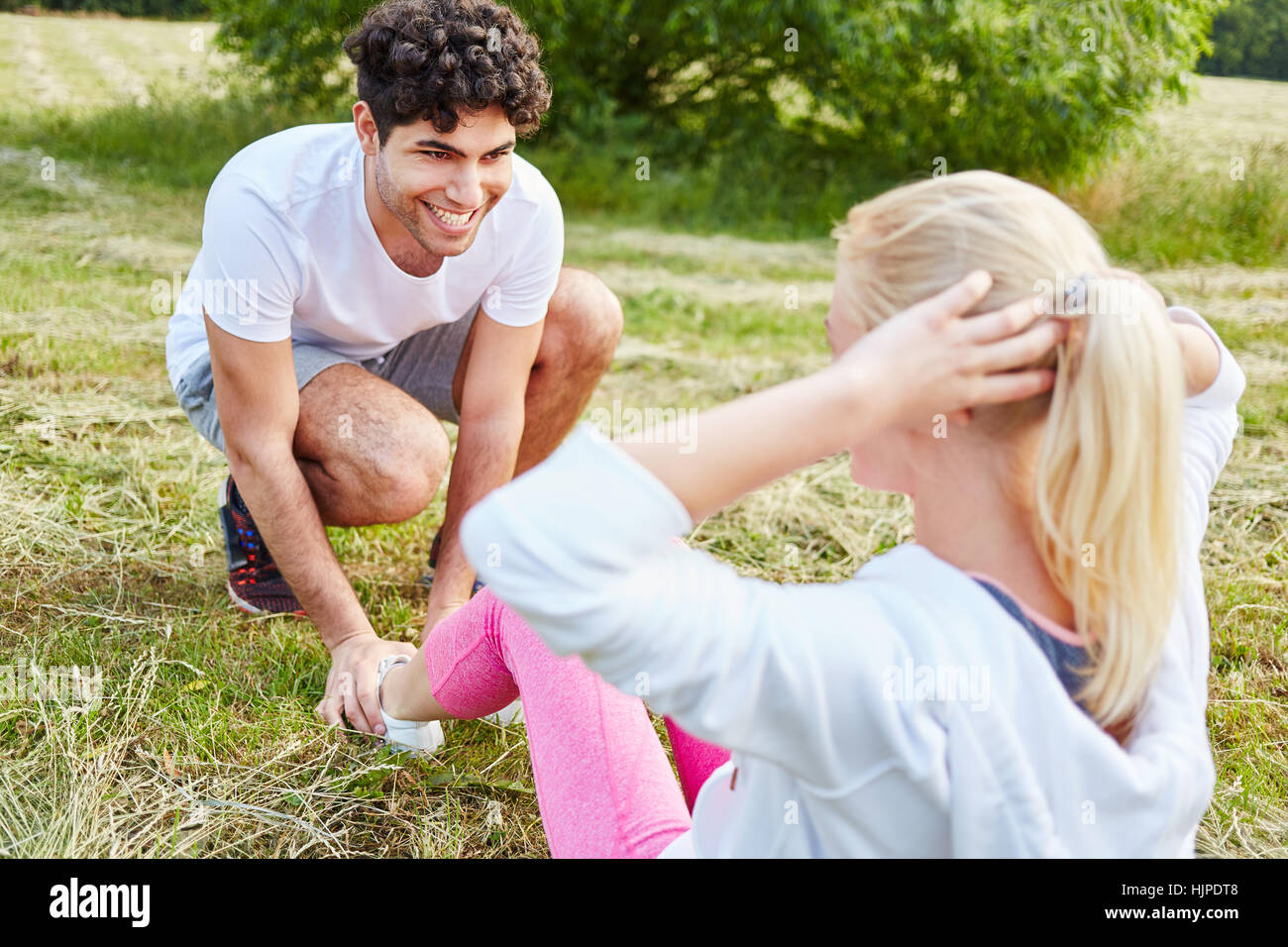 Young man helps woman with training sit-up exercise Stock Photo