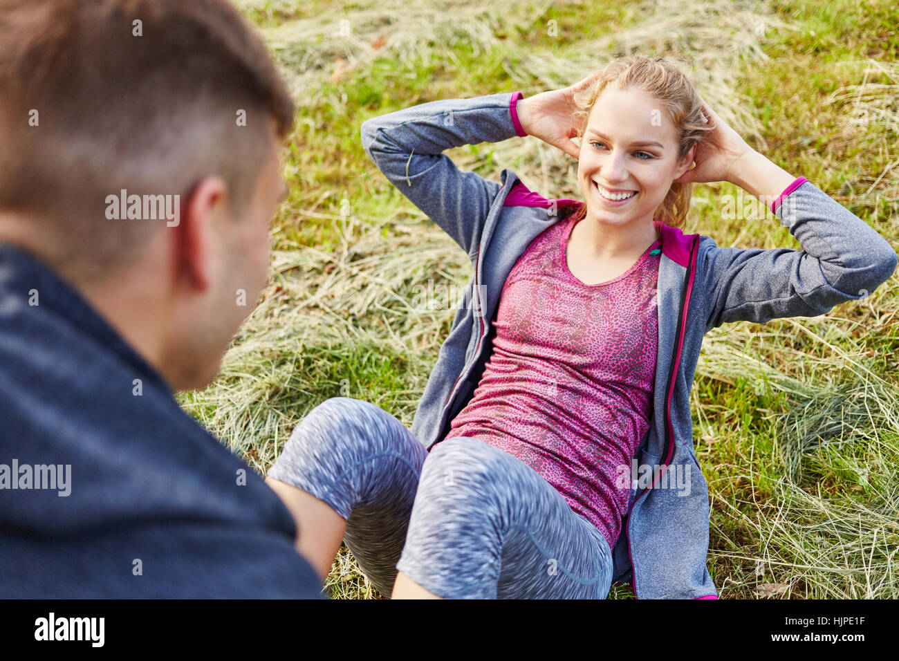 Man helps woman with sit-ups after power training Stock Photo