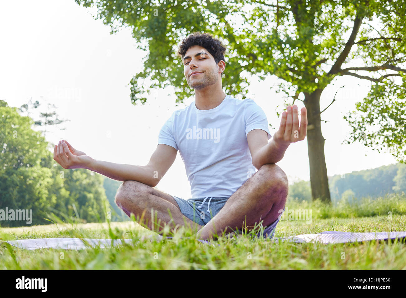Young man makes breathing yoga exercise and meditates Stock Photo