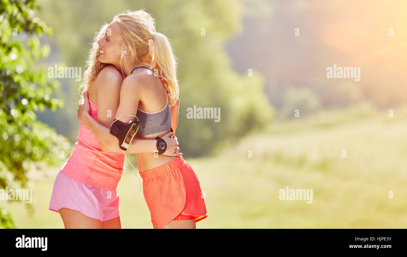 Two women embrace each other in a hug after fitness training Stock Photo
