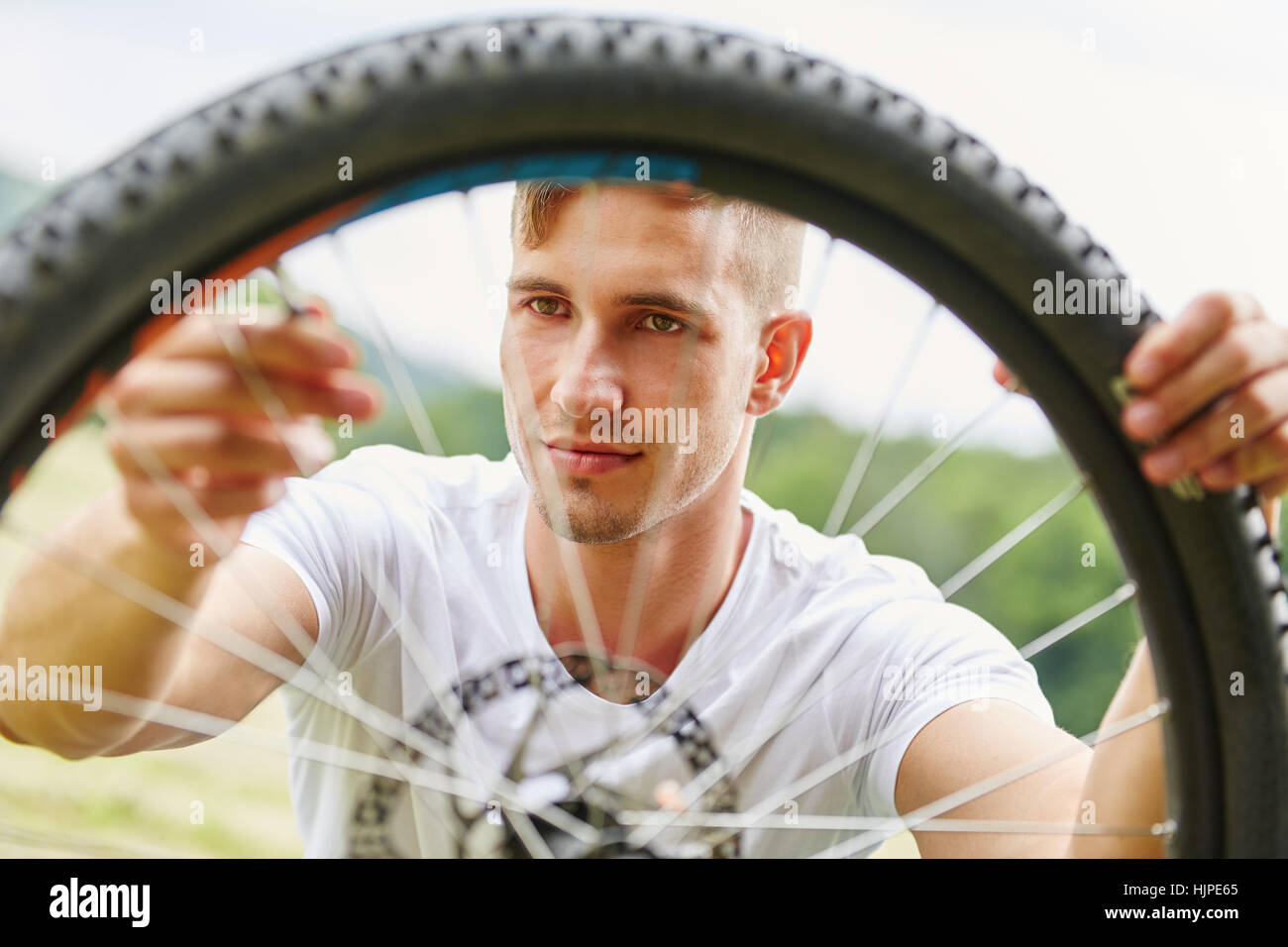 Young man repairs tire hoop of mountainbike after breakdown Stock Photo