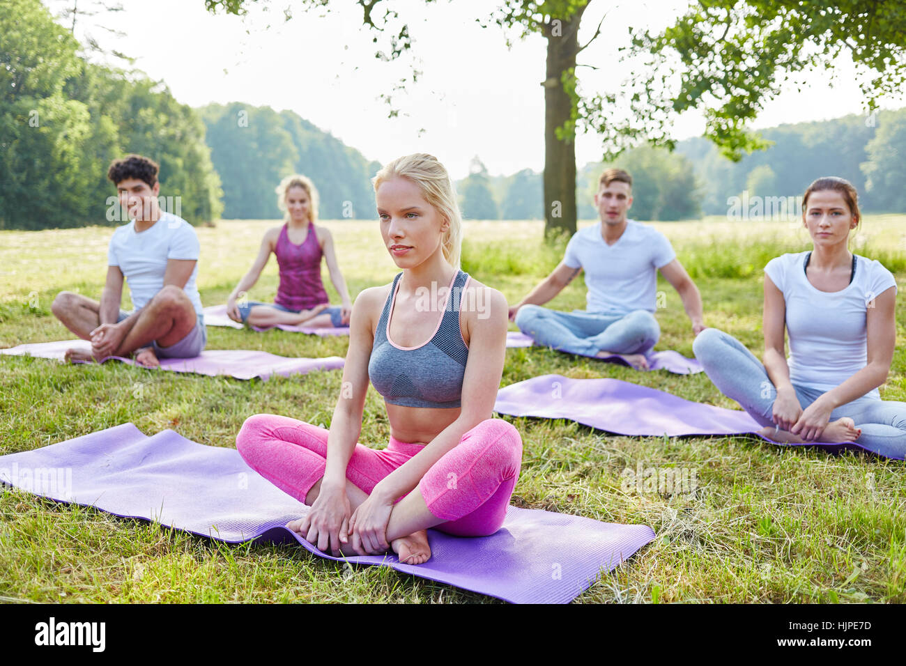 Wellness group doing yoga for relaxation in summer Stock Photo
