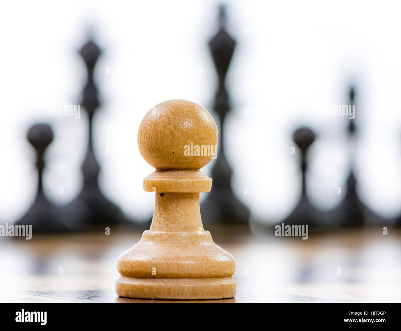 White pawn against a superiority of black chess pieces on a chess board. Selective focus. Stock Photo