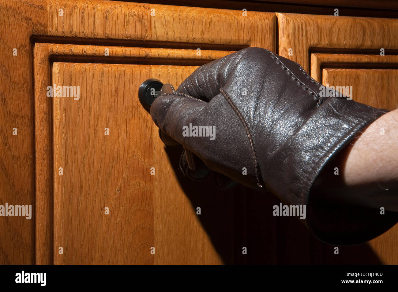 Leather gloved hand turning key in lock of wooden desk Stock Photo Alamy