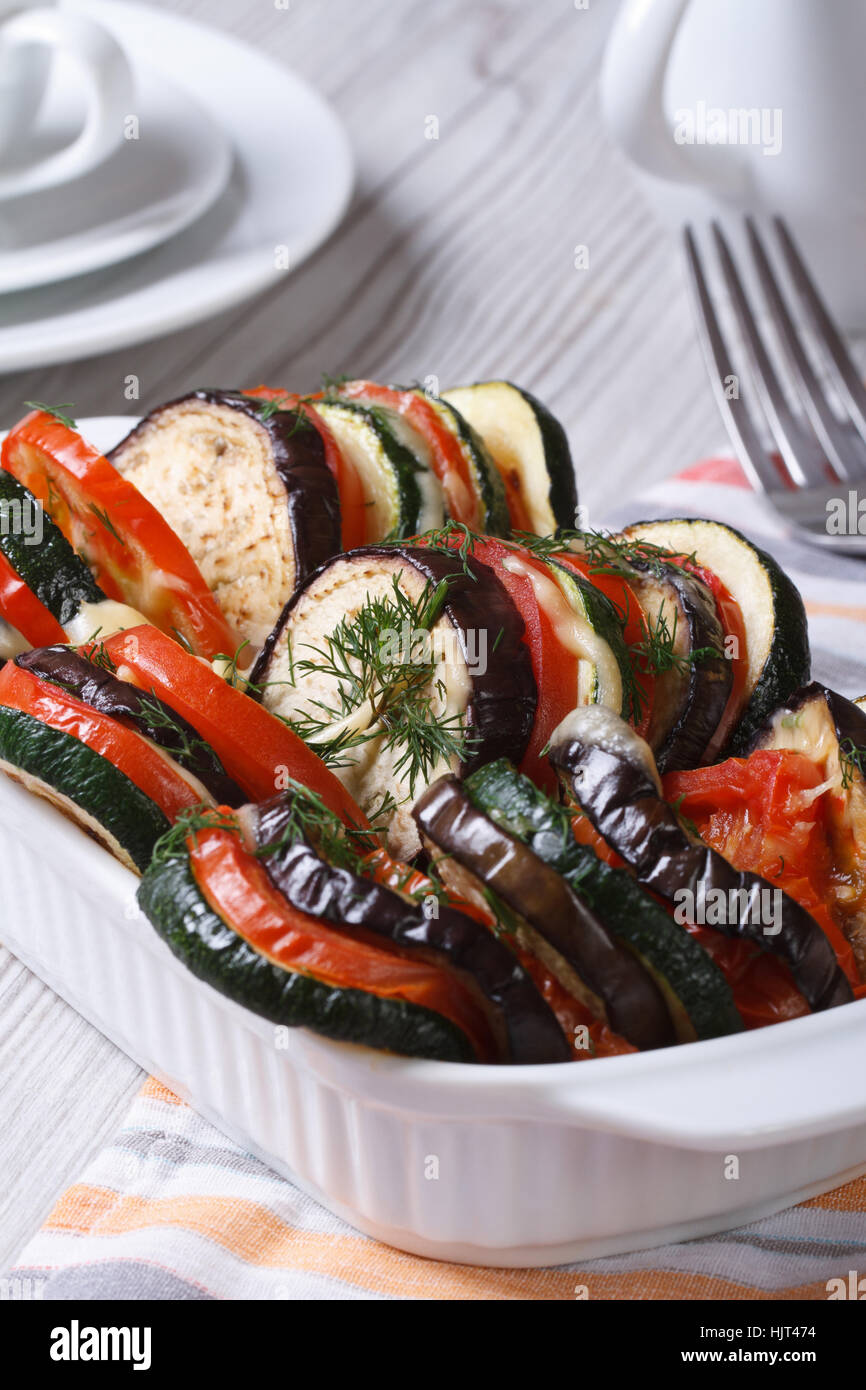 Baked vegetables tomatoes, zucchini and eggplant with cheese in baking dish close up on the table. vertical Stock Photo