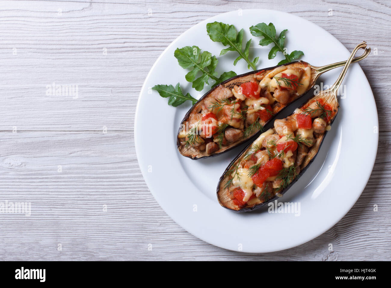 Half baked eggplants with meat, cheese and tomatoes on wooden